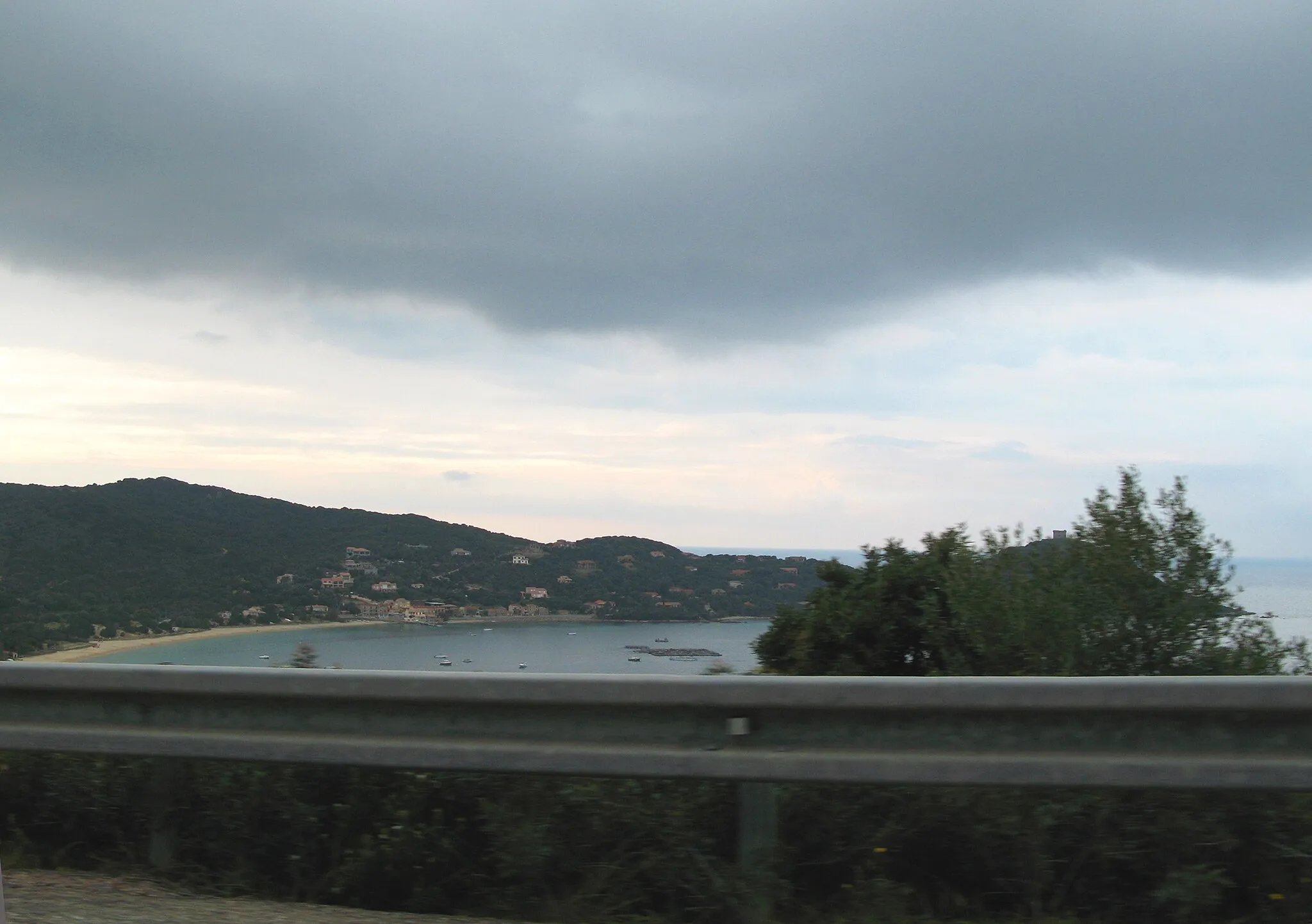 Photo showing: Belvédère-Campomoro (Corse-du-Sud, France)
La plage de Campomoro et la tour génoise, photographiées dans des conditions difficiles : depuis un véhicule en mouvement sur la route départementale D 121 (se dirigeant vers Propriano) et avec des arbres, talus ou autres obstacles surgissant brusquement dans le champ.
On aperçoit juste le "cylindre" de la tour au sommet du buisson qui cache malencontreusement le promontoire.

Camera location 41° 37′ 53.57″ N, 8° 49′ 36.89″ E View this and other nearby images on: OpenStreetMap 41.631547;    8.826914