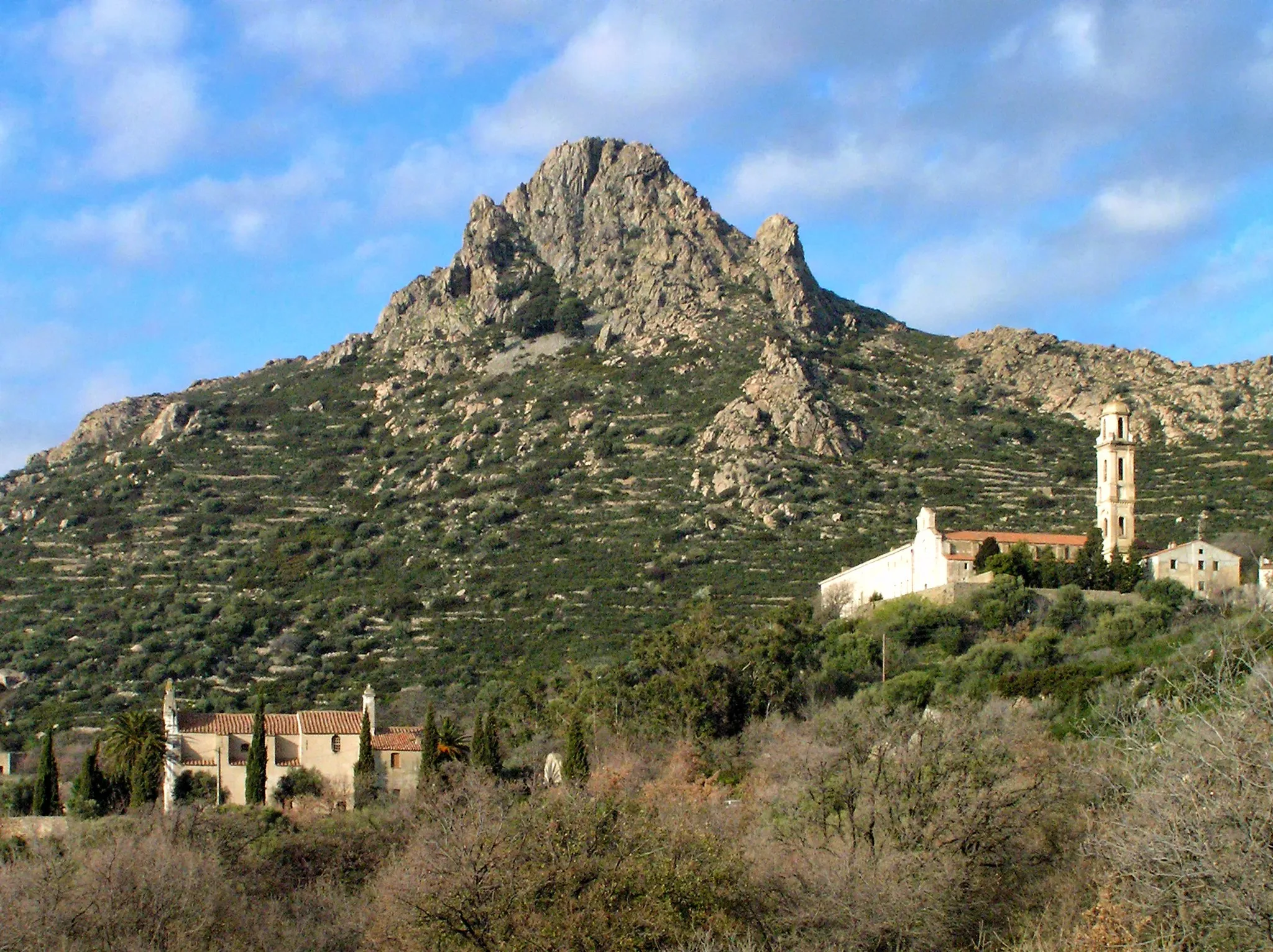 Photo showing: Corbara, Balagne (Corse) - Monte Sant'Angelo (562 m) vu du verant méridional. À l'arrière du sommet, sont les vestiges du castrum Sant' Angelo. À l'avant, le sanctuaire Notre-Dame de Lazio et le couvent de Corbara.