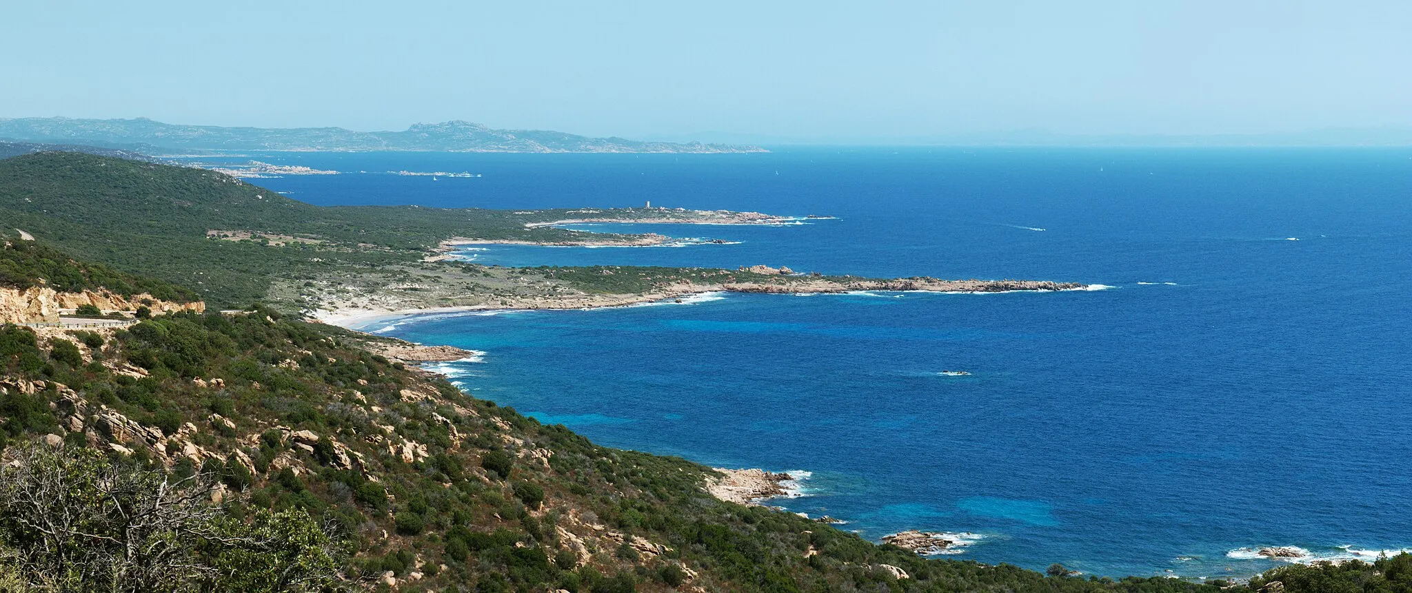 Photo showing: View of the south-western extremity of Corsica, from the N196 road near Roccapina (a place known as the "road curve to the far south").
The capes from the nearest to the farthest are:

the Punta di Mucchju Biancu, and the beach of Mucchju Biancu on the left
a nameless cape
the Punta di Caniscione, and the Olmeto genoese tower
the Bruzzi peninsula and the Bruzzi islands
the Punta di Capineru
the Punta di Ventilegne
the Capo di Feno (the largest cape, on the background) with a small lighthouse There is a monastery in the highest point of the Capo di Feno: the Ermitage de la Trinité.

Northern Sardinia is also barely visible, 50km away.
