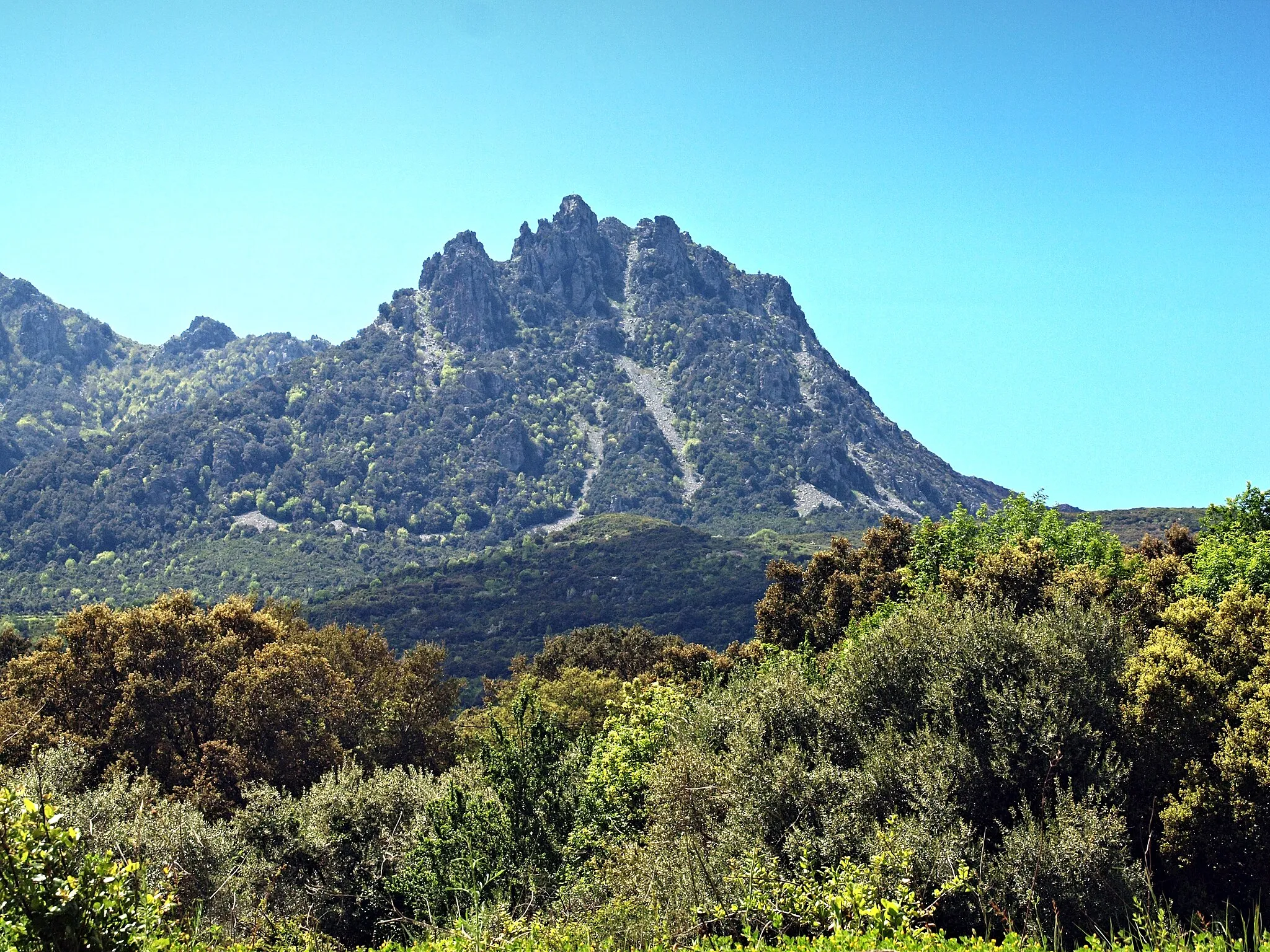 Photo showing: Sisco, Cap Corse (Corse) - Les aiguilles du Pinzalone, rocher dominant la vallée au sommet duquel se dresse une croix (1 030 mètres)