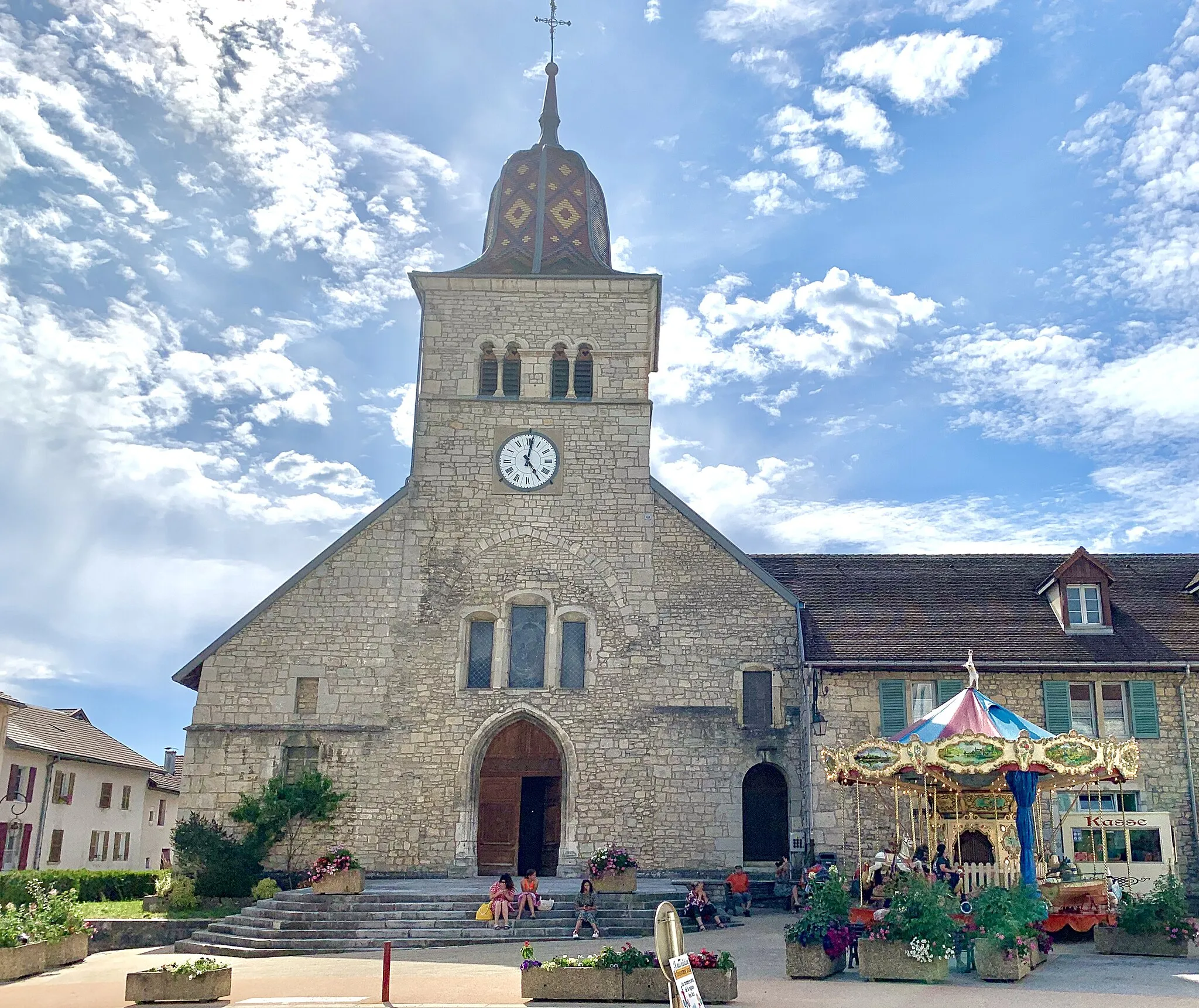 Photo showing: L’église Saint-Nithier de Clairvaux-les-Lacs dans le Jura, avec un petit carrousel, dans une atmosphère légère et estivale.