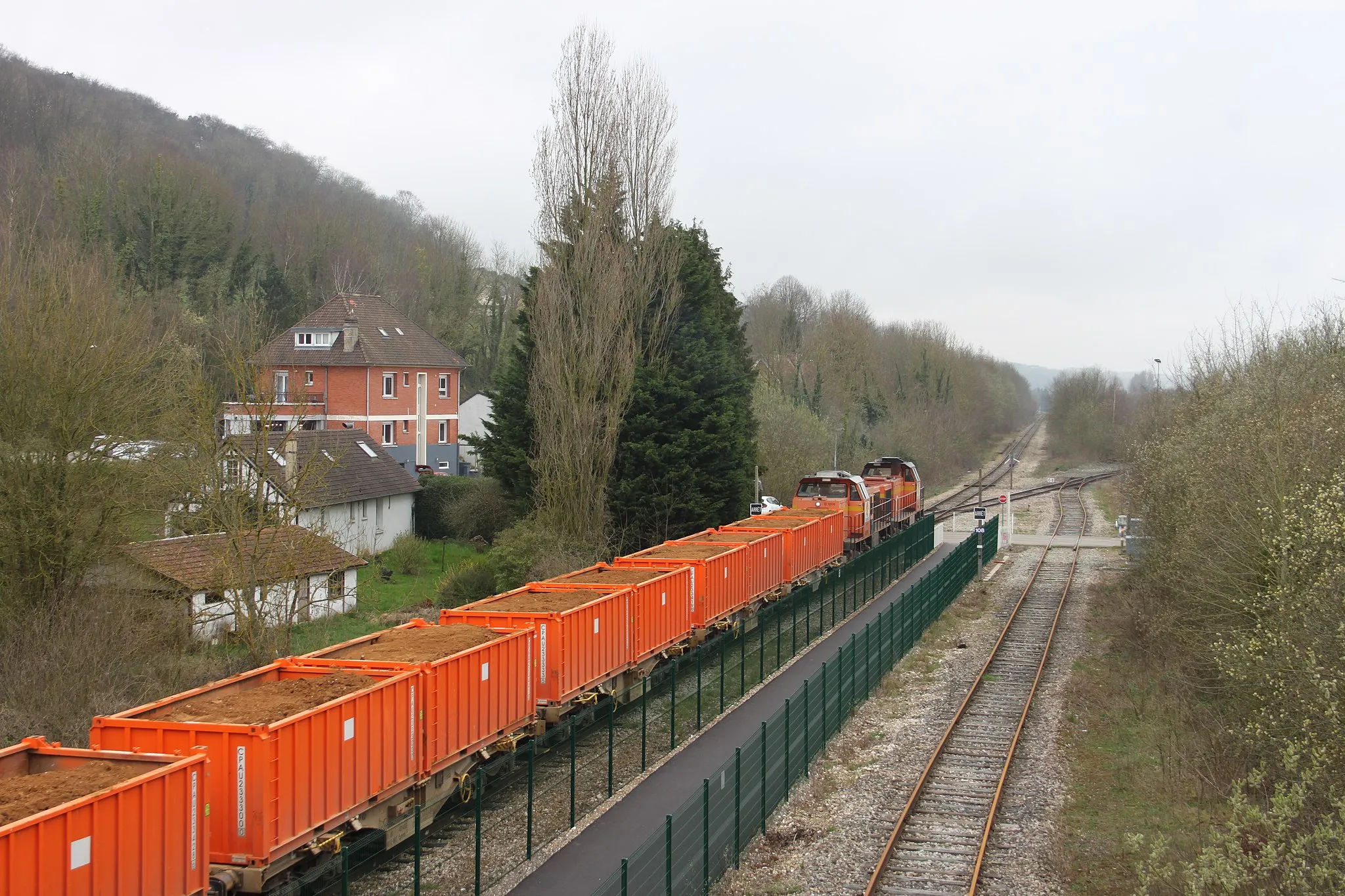 Photo showing: Rouxmesnil-Bouteilles, PN108, départ (après refoulement du faisceau de voies de garages) d'un train de terre pour le Terminal Forestier du port de Rouen (via changement de bout en gare de Dieppe) . Tiré par les Vossloh G 1206 COLAS RAIL n°10 et 13 . Remarquer un quai à voyageur vestige de la gare de Rouxmesnil et plus loin au fond le PN109, à droite naissance de la ligne de Rouxmesnil à Eu .