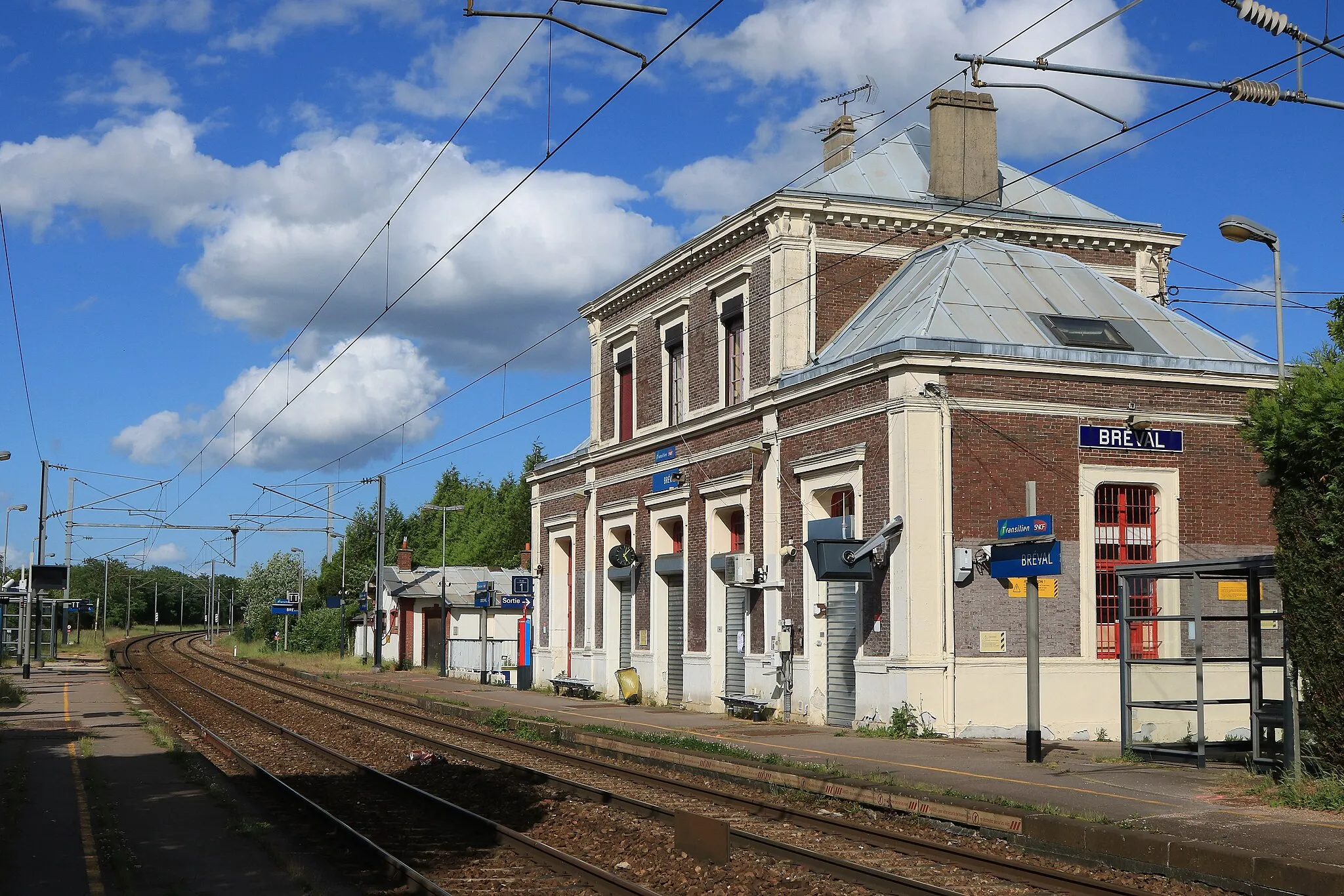 Photo showing: Bâtiment voyageurs de la gare de Bréval, quais et voies vus en direction de Paris.