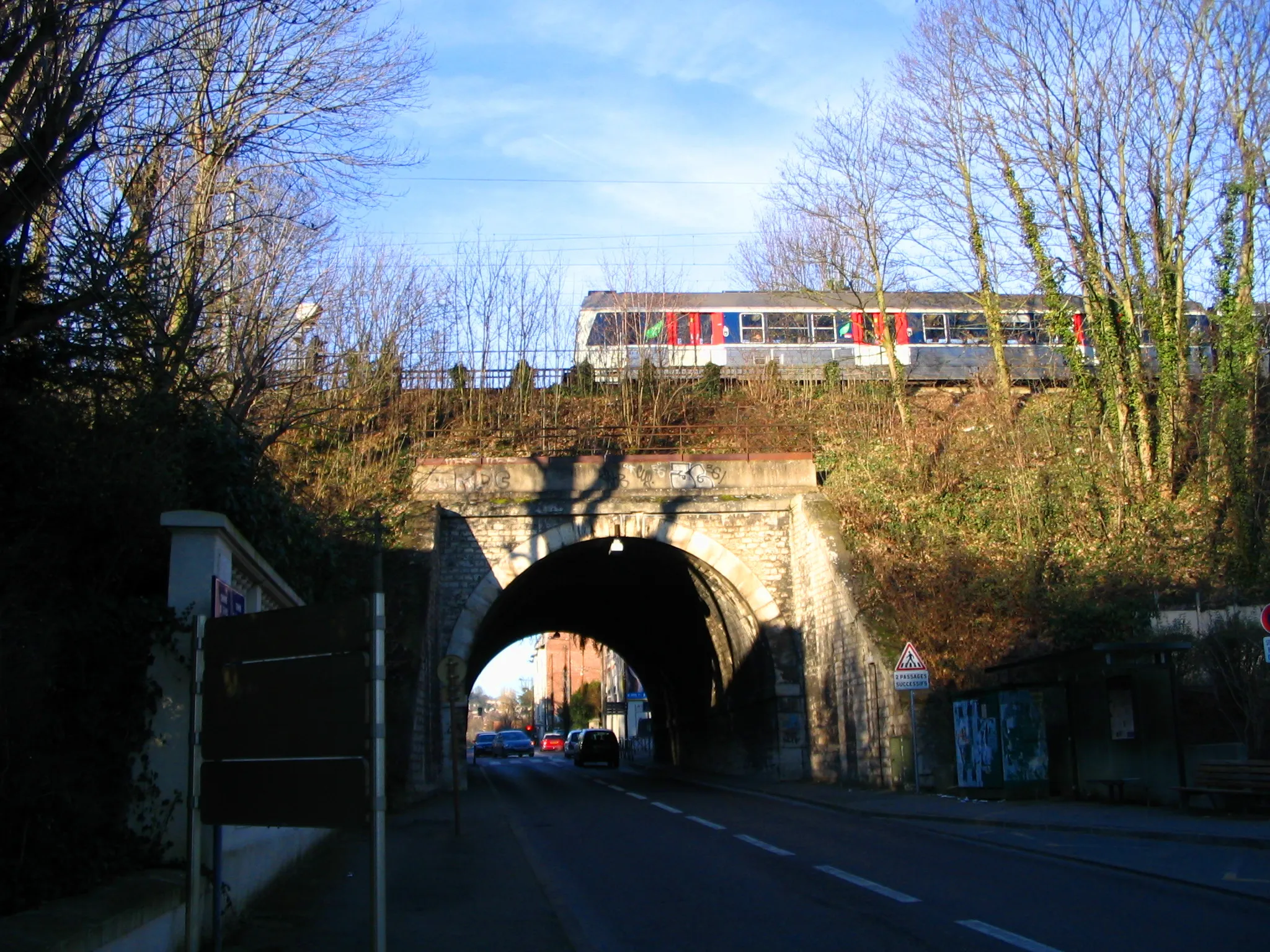 Photo showing: Rail bridge over a street near the train station of Sèvres - Ville d'Avray, Hauts-de-Seine, France, with a train to Versailles -  Rive Droite / La Verrière on it.