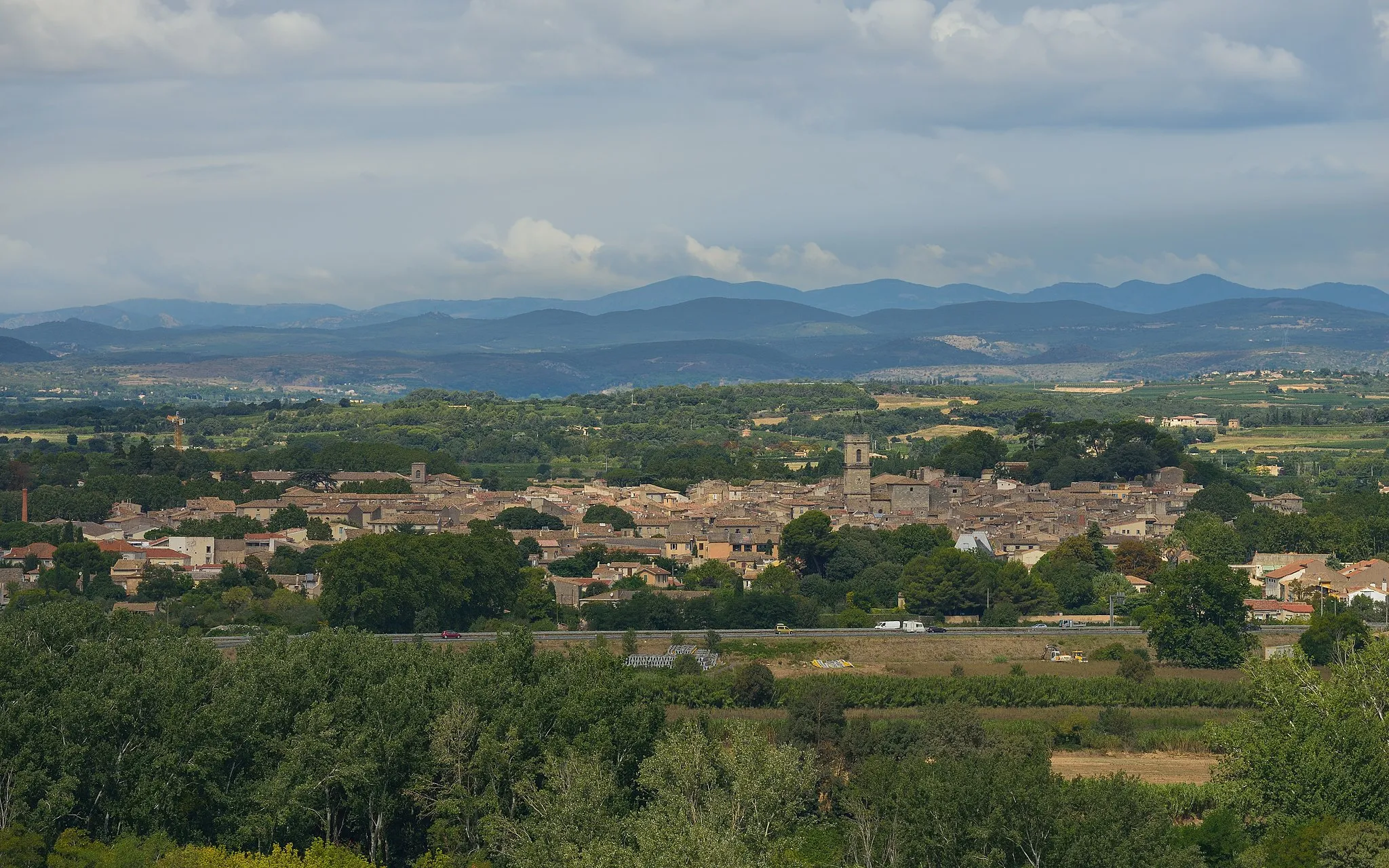 Photo showing: General view of Pézenas and the A75 autoroute from the Southeast in the commune of Castelnau-de-Guers, Hérault, France.