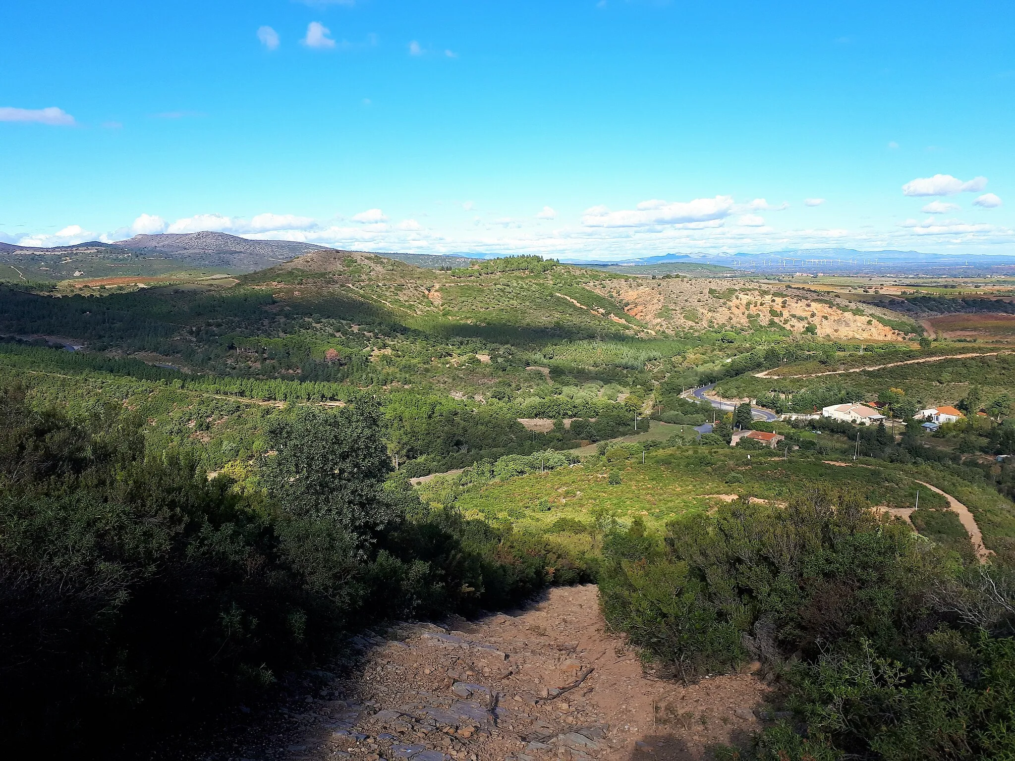 Photo showing: La ligne qui sépare les Aspres (Paléozoïque) de la plaine du Roussillon (Néogène) traverse la commune. A partir de ce point, à environ un kilomètre à l'est du village de Montauriol, on trouve des schistes gris du Cambrien au premier plan et des dépôts pliocènes ocre-rouge du Puig Tallat au second plan. (Le Roc de Majorque, sur des marbres dévoniens, près du village de Castelnou, est au fond à gauche).