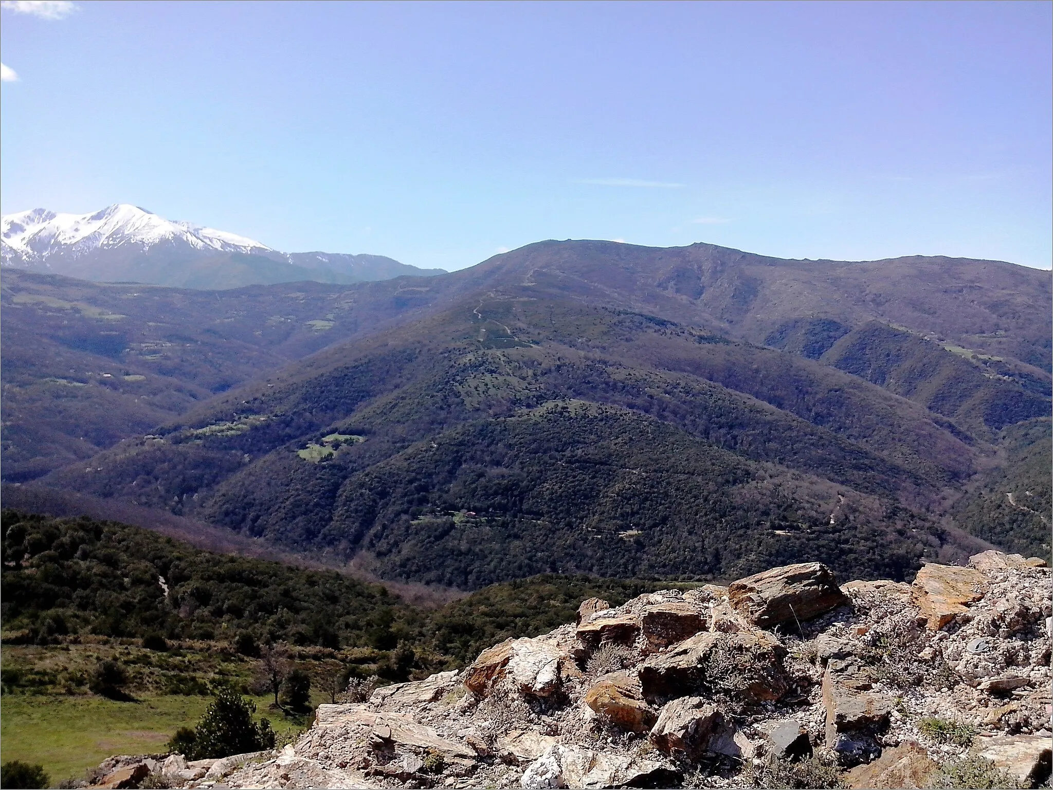 Photo showing: View to the west from the remains of Belpuig castle across the Boulès valley to Santa Anna dels Quatre Termes, a summit at 1348 metres altitude in the Pyrénées-Orientales, France.
The snow-capped area to the left is the Massif du Canigou.