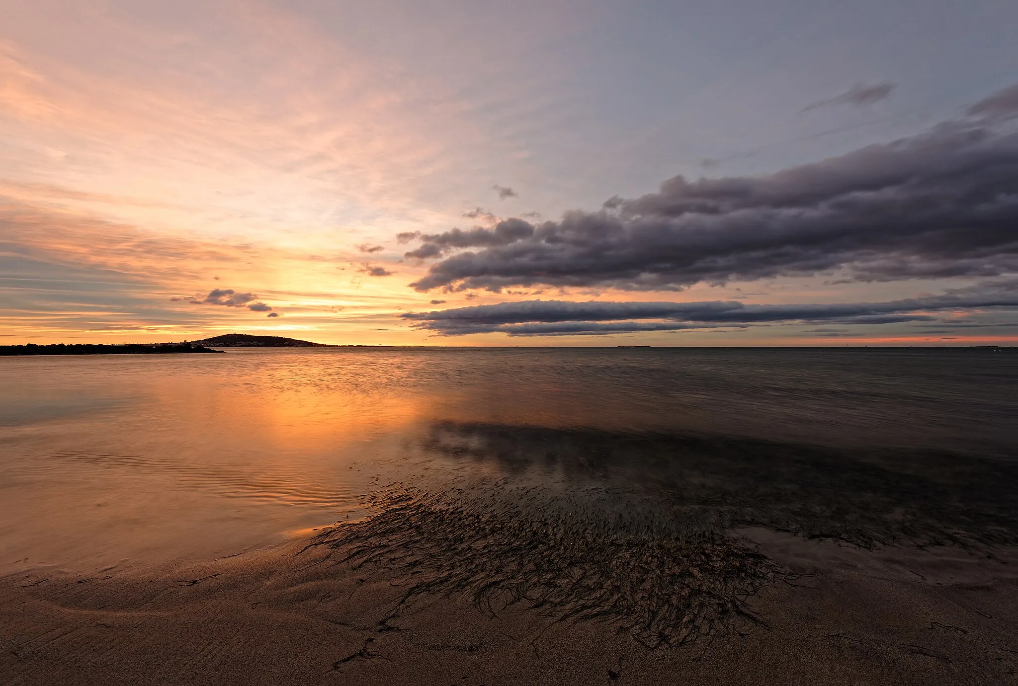 Photo showing: Sunrise and clouds over the Étang de Thau. Sète is in the background on the left. From the beach in Mèze - Hérault, France