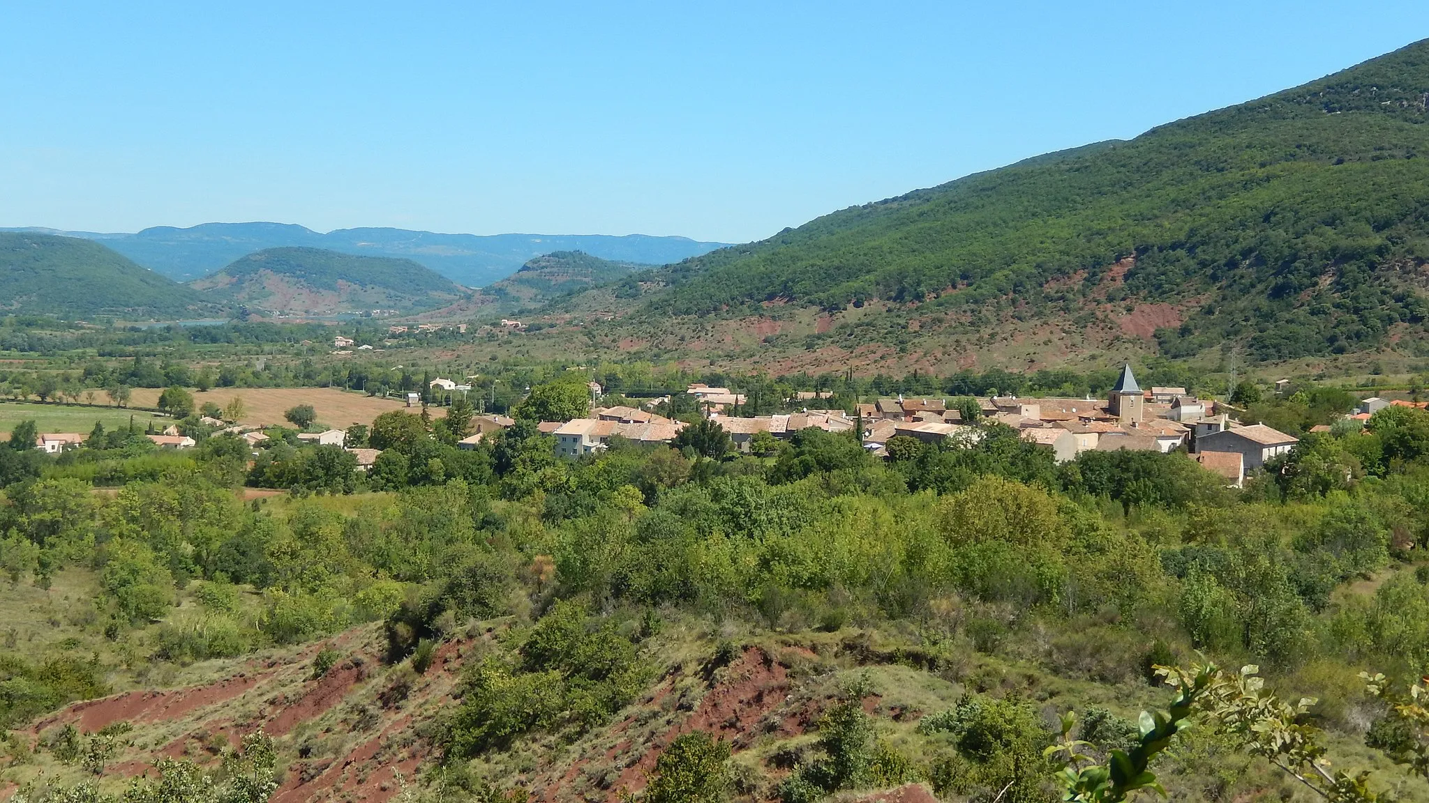 Photo showing: Le village de Salasc (Hérault, France) vu depuis le sentier des béals, qui traverse des hauteurs situées au sud-ouest. Au premier plan, des ruffes, caractéristiques des sols de la région. Au fond, on aperçoit le lac du Salagou. (La géolocalisation de cette image est approximative.)