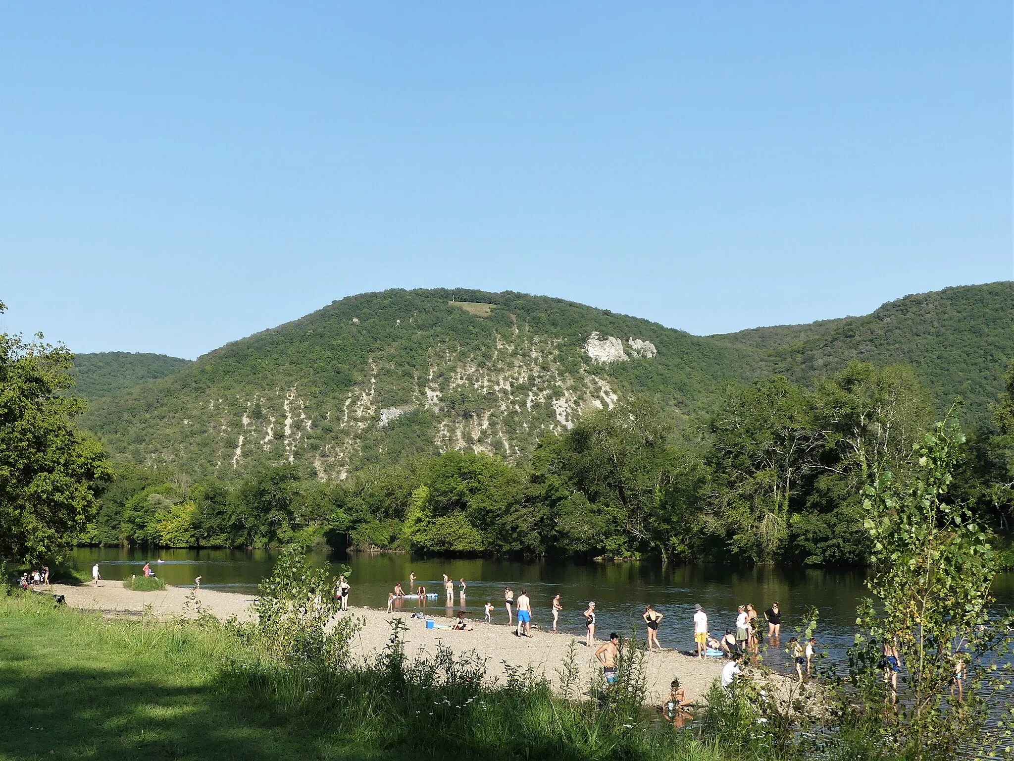 Photo showing: La petite plage de Cazoulès au bord de la Dordogne, département de la Dordogne, France. Vue prise en direction de l'amont. Sur la rive opposée, dans le département du Lot, le rocher du Bouc partagé entre les communes de Lanzac (à gauche) et Le Roc (à droite).