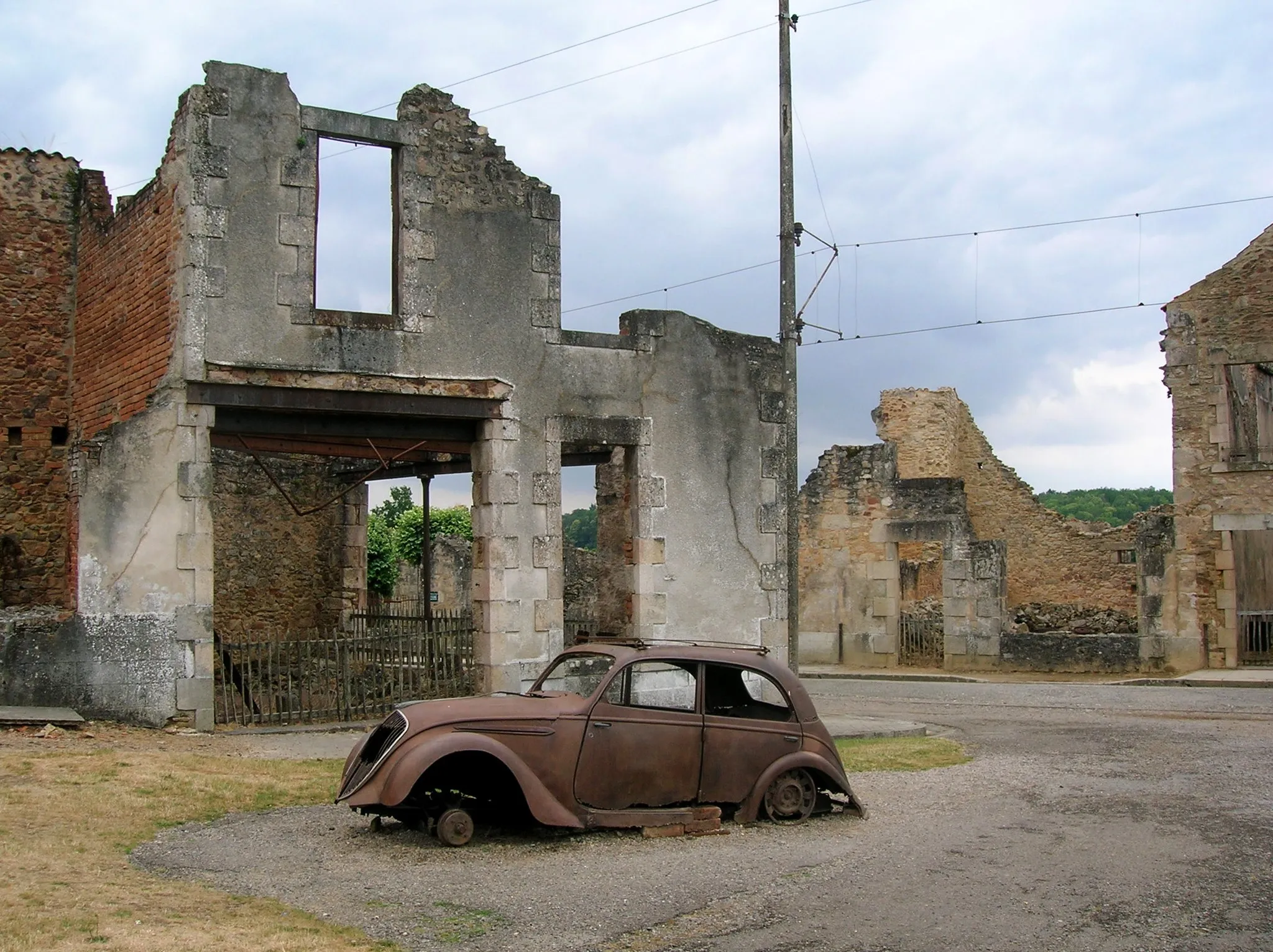 Photo showing: Decayed Peugeot 202 and some buildings in Oradour-sur-Glane.