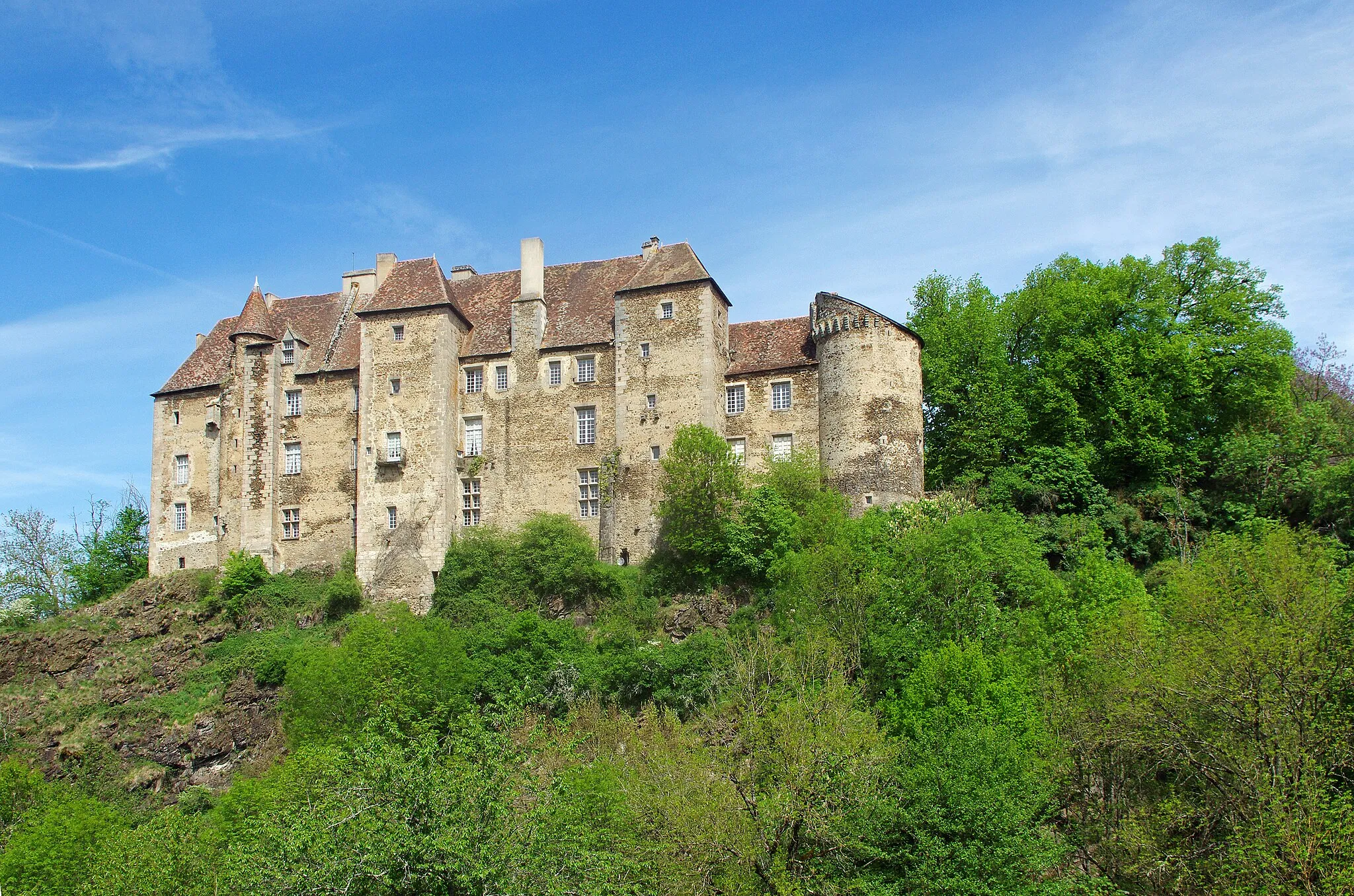 Photo showing: Boussac (Creuse).
Le château de Boussac.
Le château domine la vallée de la Petite-Creuse.
Le château fut érigé au 12éme siècle et en partie détruit par les anglais pendant la guerre de Cent Ans.
Au 15ème siècle, Jean Ier de Brosse, maréchal de France et compagnon de Jeanne d'Arc fit reconstruire le château. Le château a été remanié aux 16éme et 17éme siècles.
George Sand résida dans le château à deux reprises, pour fuir une épidémie de variole à Nohant* et durant la guerre de 1870.
George Sand décrit le château de Boussac, dans son premier roman champêtre Jeanne*.

"La ville de Boussac, formant, avec le bourg du même nom, une population de dix-huit à dix-neuf cents âmes, peut être considérée comme une des plus chétives et des plus laides sous-préfectures du centre. Ce n’est pourtant pas l’avis du narrateur de cette histoire. Jeté sur des collines abruptes, le long de la Petite-Creuse, au confluent d’un autre ruisseau rapide, Boussac offre un assemblage de maisons, de rochers, de torrents, de rues mal agencées, et de chemins escarpés, qui lui donnent une physionomie très pittoresque.
(...)
Boussac a le bon goût de se lier si bien au sol, qu’on y peut faire une belle étude de paysage à chaque pas en pleine rue. Mais il se passera bien du temps avant que les citadins de nos provinces comprennent que la végétation, la perspective, le mouvement du terrain, le bruit du torrent et les masses granitiques font partie essentielle de la beauté des villes qui ne peuvent prétendre à briller par leurs monuments. Il y a cependant un monument à Boussac, c’est le château d’origine romaine que Jean de Brosse, le fameux maréchal de Boussac, fit reconstruire en 1400 à la mode de son temps. Il est irrégulier, gracieux et coquet dans sa simplicité. Cependant les murs ont dix pieds d’épaisseur, et dès qu’on franchit le seuil, on trouve que l’intérieur a la mauvaise mine de tous ces grands brigands du moyen âge que nous voyons dans nos provinces dresser encore fièrement la tête sur toutes les hauteurs.
Ce château est moitié à la ville et moitié à la campagne. La cour et la façade armoriée regardent la ville ; mais l’autre face plonge avec le roc perpendiculaire qui la porte jusqu’au lit de la Petite-Creuse, et domine un site admirable, le cours sinueux du torrent encaissé dans les rochers, d’immenses prairies semées de châtaigniers, un vaste horizon, une profondeur à donner des vertiges. Le château, avec ses fortifications, ferme la ville de ce côté-là."
(George Sand - Jeanne)

Les Prussiens envahissent Paris le 19 septembre 1870. Pendant la même période, la variole se répand à Nohant. Son fils et ses deux petites-filles étaient déjà tombé gravement malade de la variole charbonneuse au début de l’année. Son fils, Maurice,  était resté dans un état critique pendant seize jours. Pour éviter tout nouveau risque, la famille prend la décision de se réfugier à Boussac. (Correspondance, Nohant le 15 septembre et Journal 16.9.1870)
Jeanne,  jeune bergère de la Marche, est engagée comme servante à la petite ville voisine de Boussac. Trois hommes la désirent: l'avocat Marsillat, l'aristocrate Guillaume de Boussac et sir Arthur, un riche Anglais. Sir Arthur souhaite épouser Jeanne, mais elle ne peut accepter en raison d'un vœu qu'elle a fait.  Pressée par Marsillat, Jeanne, pour lui échapper, se jette par une fenêtre. Jeanne représente évidemment le Peuple face à l'aristocratie, la bourgeoisie, les notables, la richesse. Chacun tente de séduire Jeanne à sa façon.
Par exemple, l'avocat Marsillat s'adresse à l'aristocrate Guillaume de la Brosse :"Car il entre dans les idées de votre caste de perpétuer l’ignorance chez le pauvre, afin d’y perpétuer la soumission. Aussi admirez vous, en poètes, que vous prétendez être, le merveilleux qui remplit ces pauvres cervelles ; et vous ne faites qu'entretenir, par la dévotion, par la protection accordée aux images miraculeuses, aux pèlerinages, et autres niaiseries, la folie de nos pauvres villageois."