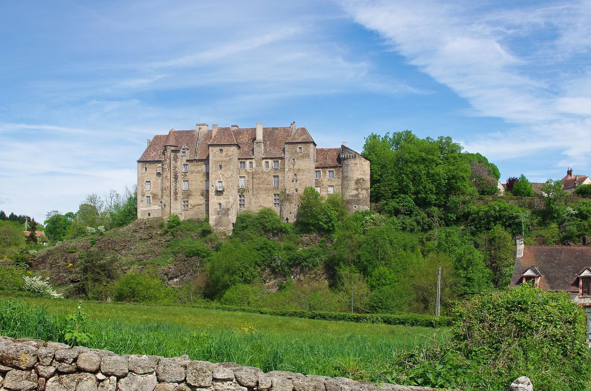 Photo showing: Boussac (Creuse).
Le château de Boussac.
Le château domine la vallée de la Petite-Creuse.
Le château fut érigé au 12éme siècle et en partie détruit par les anglais pendant la guerre de Cent Ans.
Au 15ème siècle, Jean Ier de Brosse, maréchal de France et compagnon de Jeanne d'Arc fit reconstruire le château. Le château a été remanié aux 16éme et 17éme siècles.
George sand résida dans le château à deux reprises, pour fuir une épidémie de variole à Nohant* et durant la guerre de 1870.
George Sand décrit le château de Boussac, dans son premier roman champêtre Jeanne*.

"La ville de Boussac, formant, avec le bourg du même nom, une population de dix-huit à dix-neuf cents âmes, peut être considérée comme une des plus chétives et des plus laides sous-préfectures du centre. Ce n’est pourtant pas l’avis du narrateur de cette histoire. Jeté sur des collines abruptes, le long de la Petite-Creuse, au confluent d’un autre ruisseau rapide, Boussac offre un assemblage de maisons, de rochers, de torrents, de rues mal agencées, et de chemins escarpés, qui lui donnent une physionomie très pittoresque.
(...)
Boussac a le bon goût de se lier si bien au sol, qu’on y peut faire une belle étude de paysage à chaque pas en pleine rue. Mais il se passera bien du temps avant que les citadins de nos provinces comprennent que la végétation, la perspective, le mouvement du terrain, le bruit du torrent et les masses granitiques font partie essentielle de la beauté des villes qui ne peuvent prétendre à briller par leurs monuments. Il y a cependant un monument à Boussac, c’est le château d’origine romaine que Jean de Brosse, le fameux maréchal de Boussac, fit reconstruire en 1400 à la mode de son temps. Il est irrégulier, gracieux et coquet dans sa simplicité. Cependant les murs ont dix pieds d’épaisseur, et dès qu’on franchit le seuil, on trouve que l’intérieur a la mauvaise mine de tous ces grands brigands du moyen âge que nous voyons dans nos provinces dresser encore fièrement la tête sur toutes les hauteurs.
Ce château est moitié à la ville et moitié à la campagne. La cour et la façade armoriée regardent la ville ; mais l’autre face plonge avec le roc perpendiculaire qui la porte jusqu’au lit de la Petite-Creuse, et domine un site admirable, le cours sinueux du torrent encaissé dans les rochers, d’immenses prairies semées de châtaigniers, un vaste horizon, une profondeur à donner des vertiges. Le château, avec ses fortifications, ferme la ville de ce côté-là."
(George Sand - Jeanne)

Les Prussiens envahissent Paris le 19 septembre 1870. Pendant la même période, la variole se répand à Nohant. Son fils et ses deux petites-filles étaient déjà tombé gravement malade de la variole charbonneuse au début de l’année. Son fils, Maurice,  était resté dans un état critique pendant seize jours. Pour éviter tout nouveau risque, la famille prend la décision de se réfugier à Boussac. (Correspondance, Nohant le 15 septembre et Journal 16.9.1870)
Jeanne,  jeune bergère de la Marche, est engagée comme servante à la petite ville voisine de Boussac. Trois hommes la désirent: l'avocat Marsillat, l'aristocrate Guillaume de Boussac et sir Arthur, un riche Anglais. Sir Arthur souhaite épouser Jeanne, mais elle ne peut accepter en raison d'un vœu qu'elle a fait.  Pressée par Marsillat, Jeanne, pour lui échapper, se jette par une fenêtre. Jeanne représente évidemment le Peuple face à l'aristocratie, la bourgeoisie, les notables, la richesse. Chacun tente de séduire Jeanne à sa façon.
Par exemple, l'avocat Marsillat s'adresse à l'aristocrate Guillaume de la Brosse :"Car il entre dans les idées de votre caste de perpétuer l’ignorance chez le pauvre, afin d’y perpétuer la soumission. Aussi admirez vous, en poètes, que vous prétendez être, le merveilleux qui remplit ces pauvres cervelles ; et vous ne faites qu'entretenir, par la dévotion, par la protection accordée aux images miraculeuses, aux pèlerinages, et autres niaiseries, la folie de nos pauvres villageois."