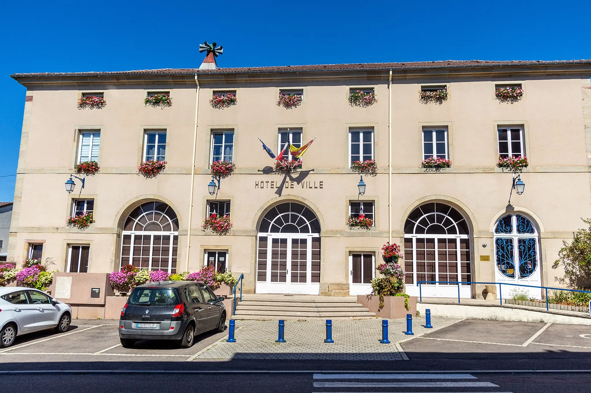 Photo showing: Hôtel de ville de Dompaire en été avec ses jardinières de géranium et ses drapeaux Européen, Français et Lorrain.
