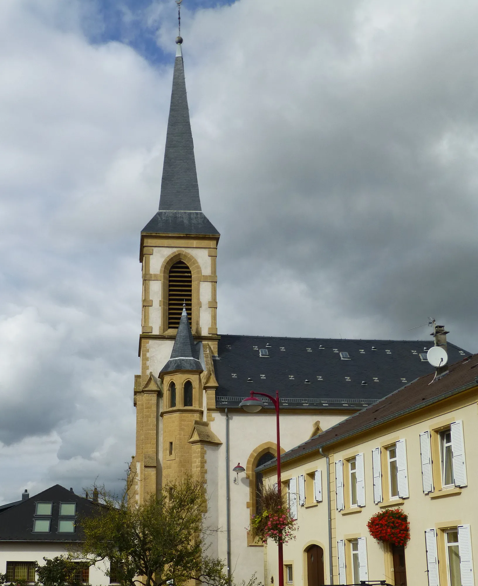 Photo showing: Church of Kuntzig, side view. Moselle department. Note the white painting (absent in the 2011 picture).