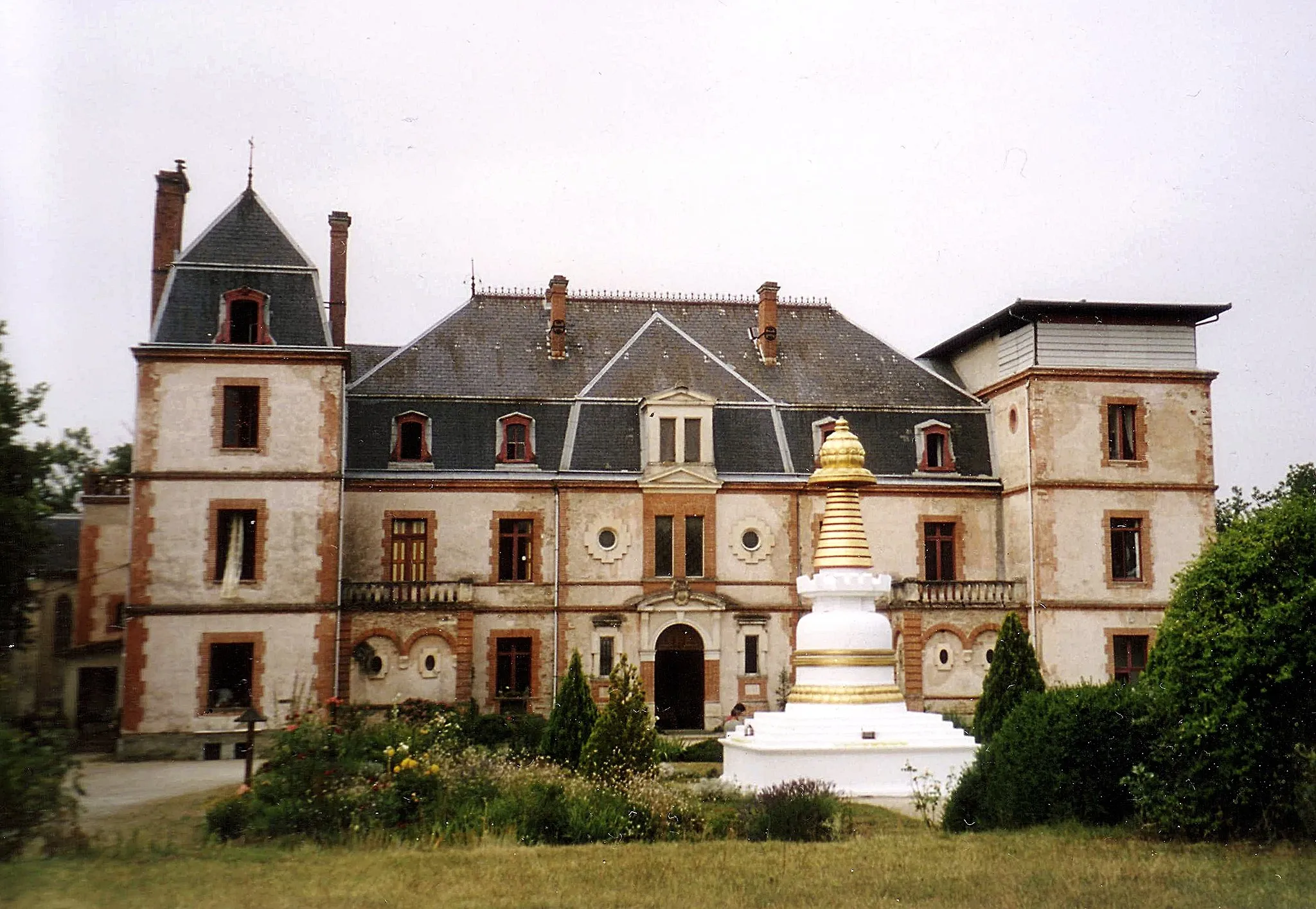 Photo showing: Stoupa devant l'institut Vajra Yogini, qui se trouve dans le Château d'en Clausade à Marzens dans le Tarn, France, non loin de Lavaur. On peut remarquer que l'une des deux ailes du château est en partie détruite. Cela a été causé par un incendie, et au lieu de réparer le château, le centre a préféré utiliser l'argent versé par les assurances pour acheter un autre bâtiment qui héberge une communauté monastique : Le monastère Nalanda.