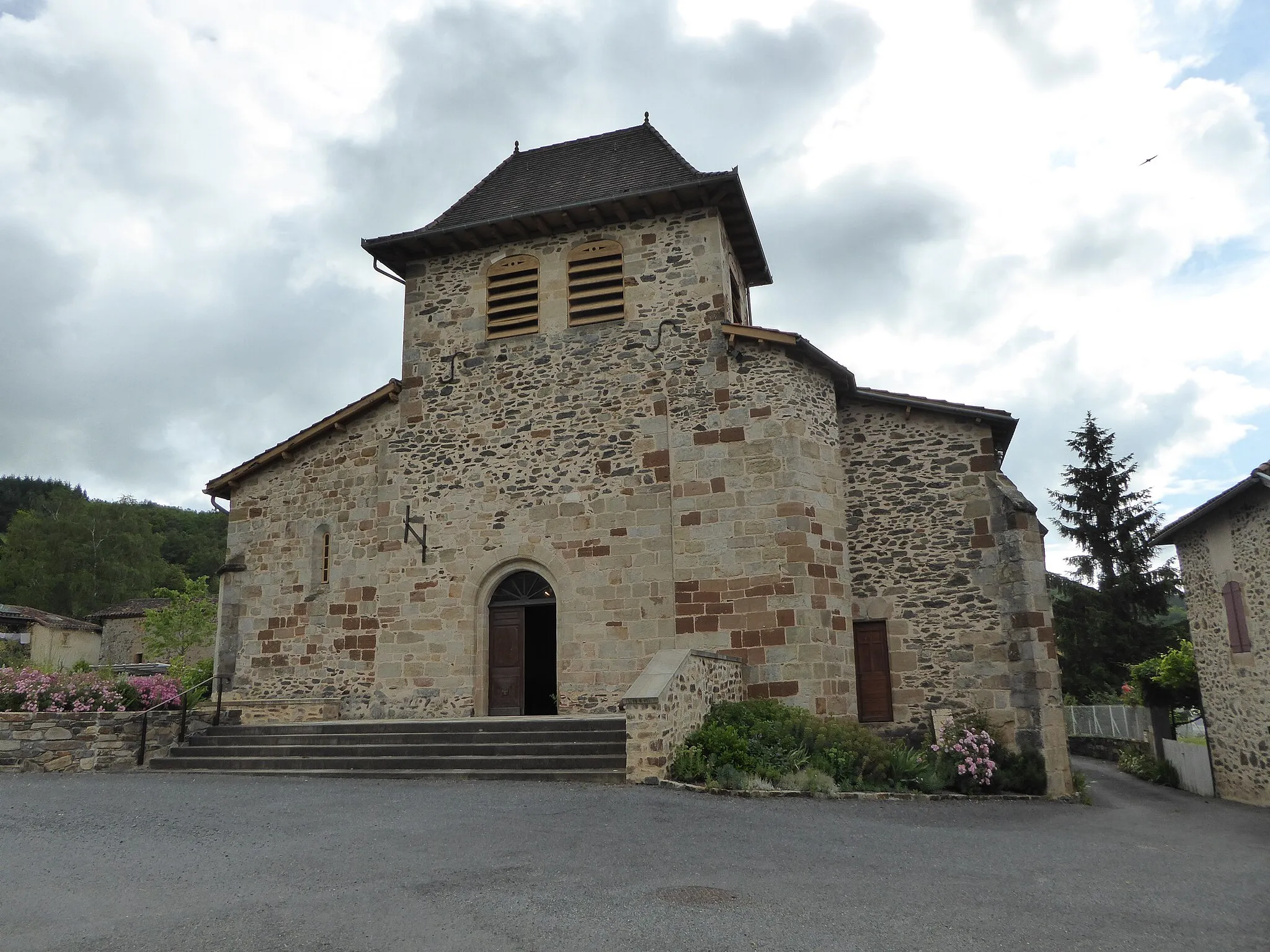 Photo showing: Le clocher de forme rectangulaire surmonte la large façade en pierres, petite porte d'entrée en plein cintre