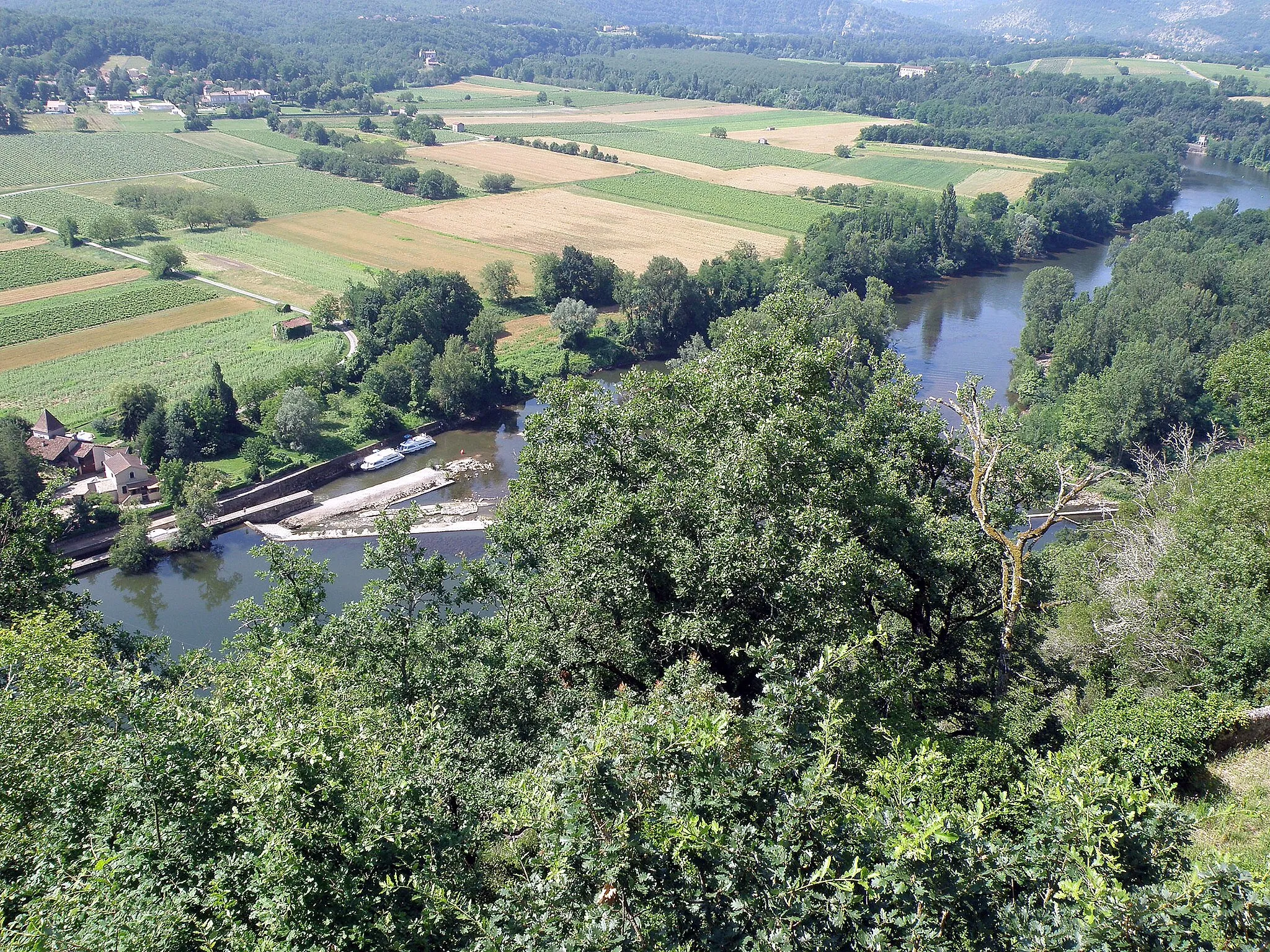 Photo showing: Mercuès, commune et village du dép. du département du Lot, région Midi-Pyrénées, France. Photographie prise depuis la terrasse ouest du château de Mercuès. Nous regardons vers le sud-sud-ouest. Vue sur le Lot, dont la rive gauche (en haut à gauche sur la photo) appartient à la comm. de Pradines. Près de nous, en bas à gauche : barrage et écluse de Mercuès, utilisée par les plaisanciers. Plus loin, la grande bâtisse à droite, au milieu des frondaisons, est le château des Bouysses (XIIIe et XIXe siècles, comm. de Mercuès).