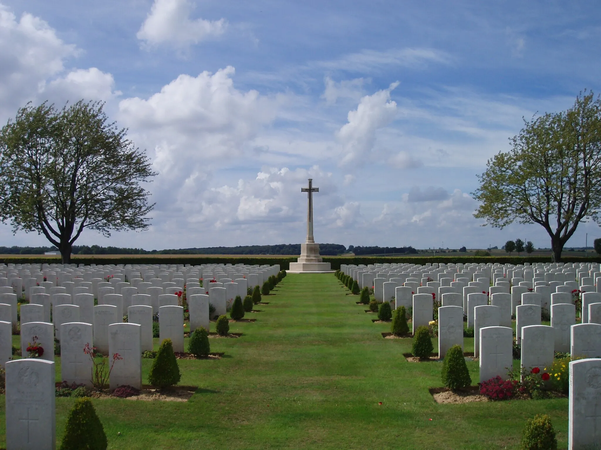 Photo showing: Part of a set of photographs of Caterpillar Valley Cemetery and the New Zealand Memorial to the Missing at this Commonwealth War Graves Commission cemetery, which is located near Longueval, France. This is the view from the central point of the cemetery, looking towards the Cross of Sacrifice.