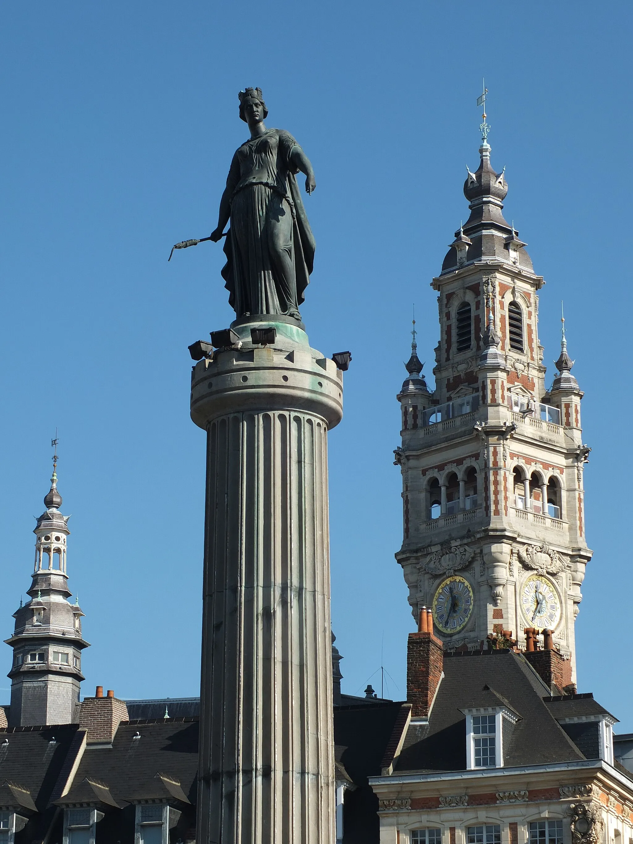 Photo showing: The Column of the Goddess in the center of the Grand′ Place (central square) of Lille. In the background are the (short) central tower and the belfry (right) of the Chamber of Commerce