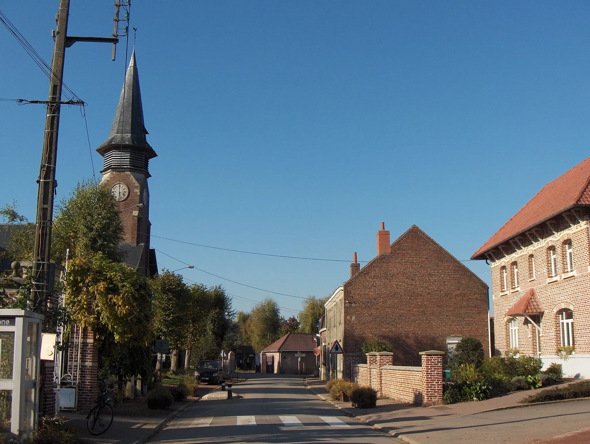 Photo showing: Le Maisnil (France, dept. Nord), centre du village, rue de l'Eglise, vue vers le nord, avec l'église Saint-Pierre à gauche et l'ancienne presbytère à droite.