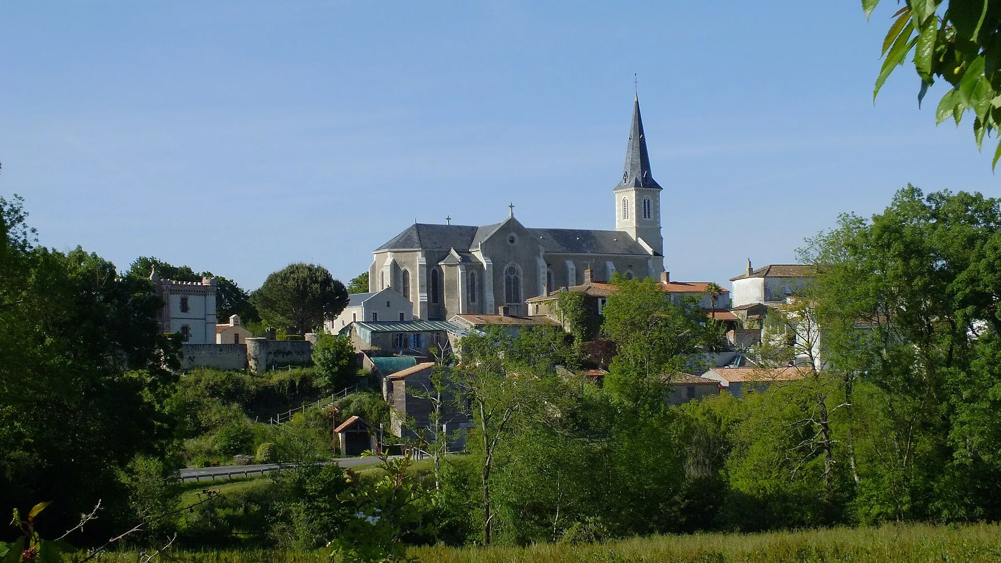 Photo showing: Eglise de plan en croix latine à transept peu saillant et chevet hémicirculaire. Le choeur se trouve à l'ouest. La partie centrale de la façade comporte un portail en ogive dépourvu de tympan,  surmonté d'une statue et d'un oculus. L'ensemble est encadré par deux contreforts.
Dans son prolongement se trouve le clocher muni de baies géminées à abat-son et d'une haute flèche polygonale de charpente. 
Les parties latérales de la façade sont arrondies et comportent chacune deux baies superposées.

Construite en 1900.