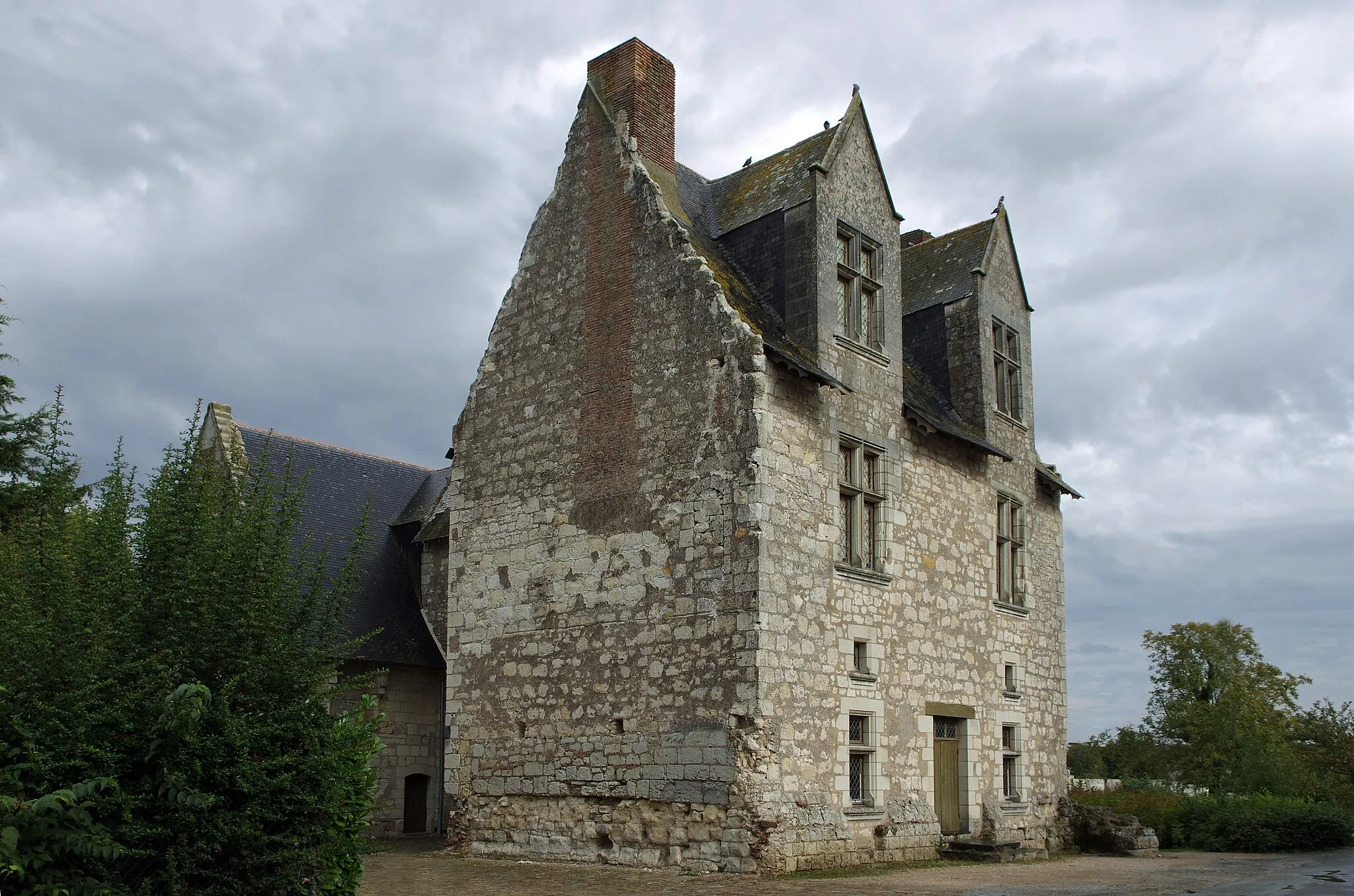 Photo showing: La Ménitré (Maine-et-Loire)
Manoir de Jeanne de Laval.
Jeanne de Laval's manor house.
L’élégant manoir, de son vrai nom « Grenier-aux-Rentes », date du XVe siècle.
Ce manoir voulut par le Roi René fut construit spécialement pour sa seconde épouse Jeanne de Laval, d’où son nom.
Jeanne de Laval qui était "douce et affectueuse", épousa René Ier d'Anjou, qui avait 24 ans de plus qu'elle et était veuf,  en septembre 1454, à Angers. A cette date, René d'Anjou, avec son maître d’œuvre Guillaume Robin*, commence les travaux  d'agrandissement et de modernisation de ses résidences de la Ménitré*, Baugé, et Launay, après s'être occupé des châteaux d'Angers et de Saumur.
Jeanne et René vécurent environ trois ans dans les manoirs des environs d'Angers et de Saumur, puis en Provence pendant cinq ans. Ils revinrent en Anjou à partir de 1462. A la mort de René d'Anjou en 1480, sans enfant, Jeanne hérita de très nombreux revenus. Elle meurt en 1498.
En 1824, la nouvelle municipalité s'installe dans le manoir, avant de construire la mairie actuelle.  La nouvelle mairie fut inaugurée en 1870 et le manoir abandonné. Le manoir connut plusieurs locataires qui transformèrent ce domaine en réserve de graines.
Les établissements Vilmorin sont propriétaires du manoir depuis 1972.
La cheminée au-dessus de la cour est le seul vestige du cabinet de travail du roi.

Guillaume Robin surveillera en particulier les travaux de la Ménitré,  tant la charpenterie que la couverture ou la maçonnerie. Dans son testament, rédigé peu de temps avant sa mort, en 1463, Guillaume Robin fait le bilan des ouvrages dont il avait la charge : Angers, Saumur, Baugé, le couvent de La Baumette, près d'Angers; mais nous savons, par ailleurs, qu'il supervise les oeuvres de La Ménitré et de Rivettes. (Les chantiers des princes angevins (1370-1480) : direction, maîtrise, main-d'oeuvre - Françoise Robin)

Les travaux de La Ménitré, n'ont sans doute pas commencé avant 1457. Travaux de longue haleine certainement repris en 1470 avec la construction d'un nouveau corps de logis. En décembre 1470, René ordonne l'édification d'un nouveau bâtiment à La Ménitré et le contrat stipule que chaque jour ouvrable seize personnes devront s'y trouver au travail. Il ne laisse que quatre mois environ aux maçons, deux à peine aux charpentiers et un peu moins aux couvreurs. www.lamenitre.fr/Manoir-Jeanne-de-Laval.html

(Voir Les chantiers des princes angevins (1370-1480) : direction, maîtrise, main-d'oeuvre - Françoise Robin)