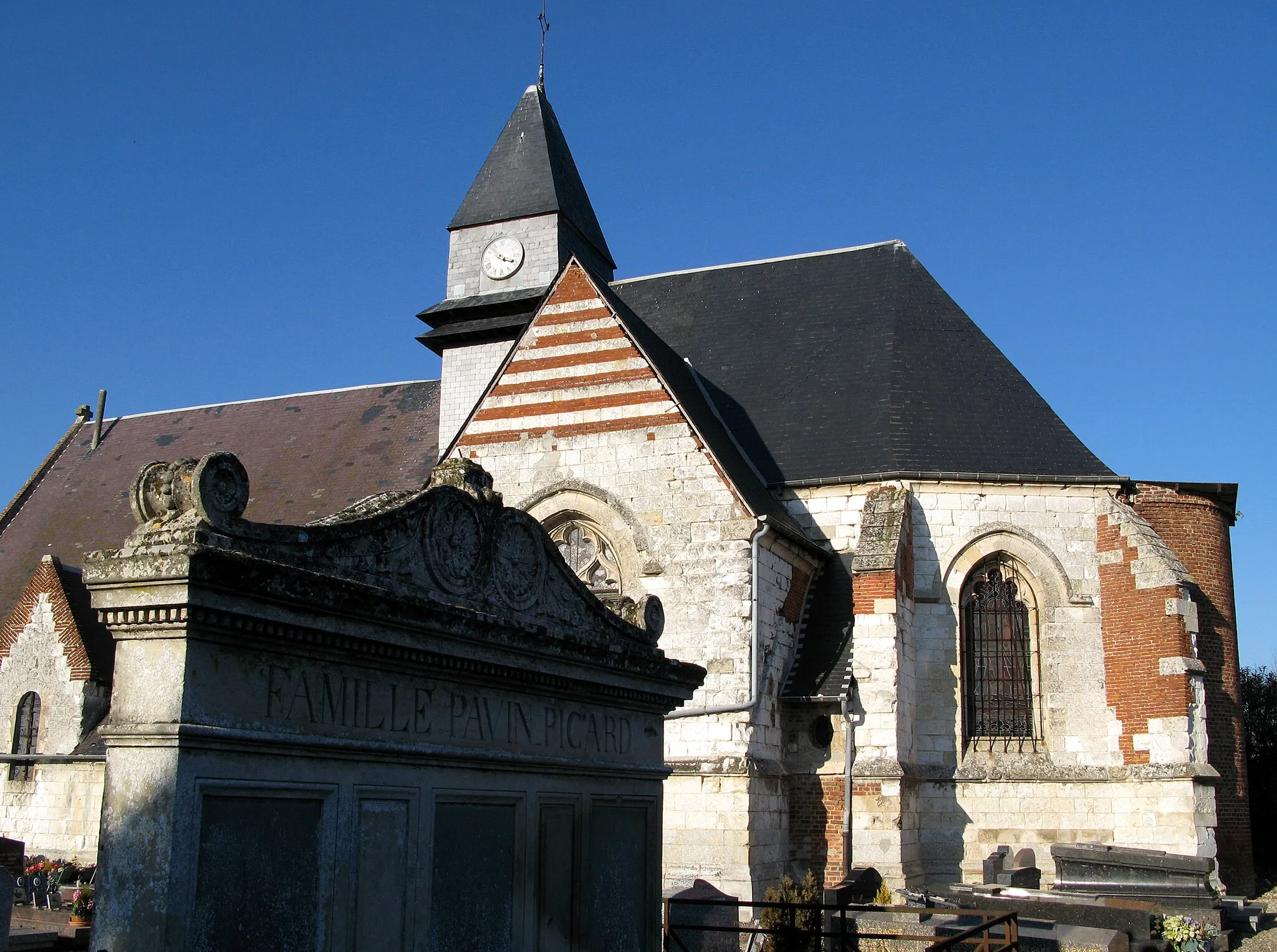 Photo showing: Louvrechy (Somme, France) -
L'église est dans le cimetière.
Par ce cadrage assez particulier (... monument funéraire cachant a priori beaucoup trop l'église), j'ai voulu "jouer" avec le rapprochement de formes circulaires :

celles du monument lui-même (une volute à chaque angle et 2 médaillons),
l'arc du haut de fenêtre de l'église juste derrière,
l'horloge du clocher.