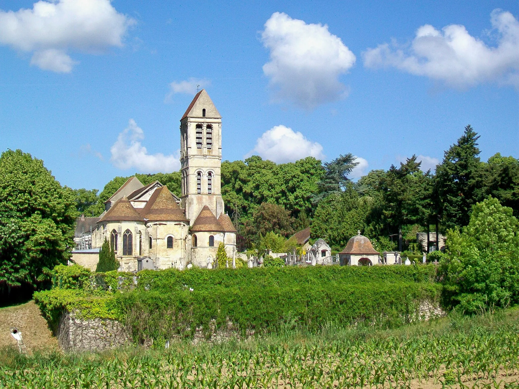 Photo showing: L'église Saint-Côme-Saint-Damien depuis le chemin de la Paroisse (GR 1 et 655). Entre le mur du cimetière et le champ de maïs, passe la D 316 dans une tranchée (déviation du centre-ville).