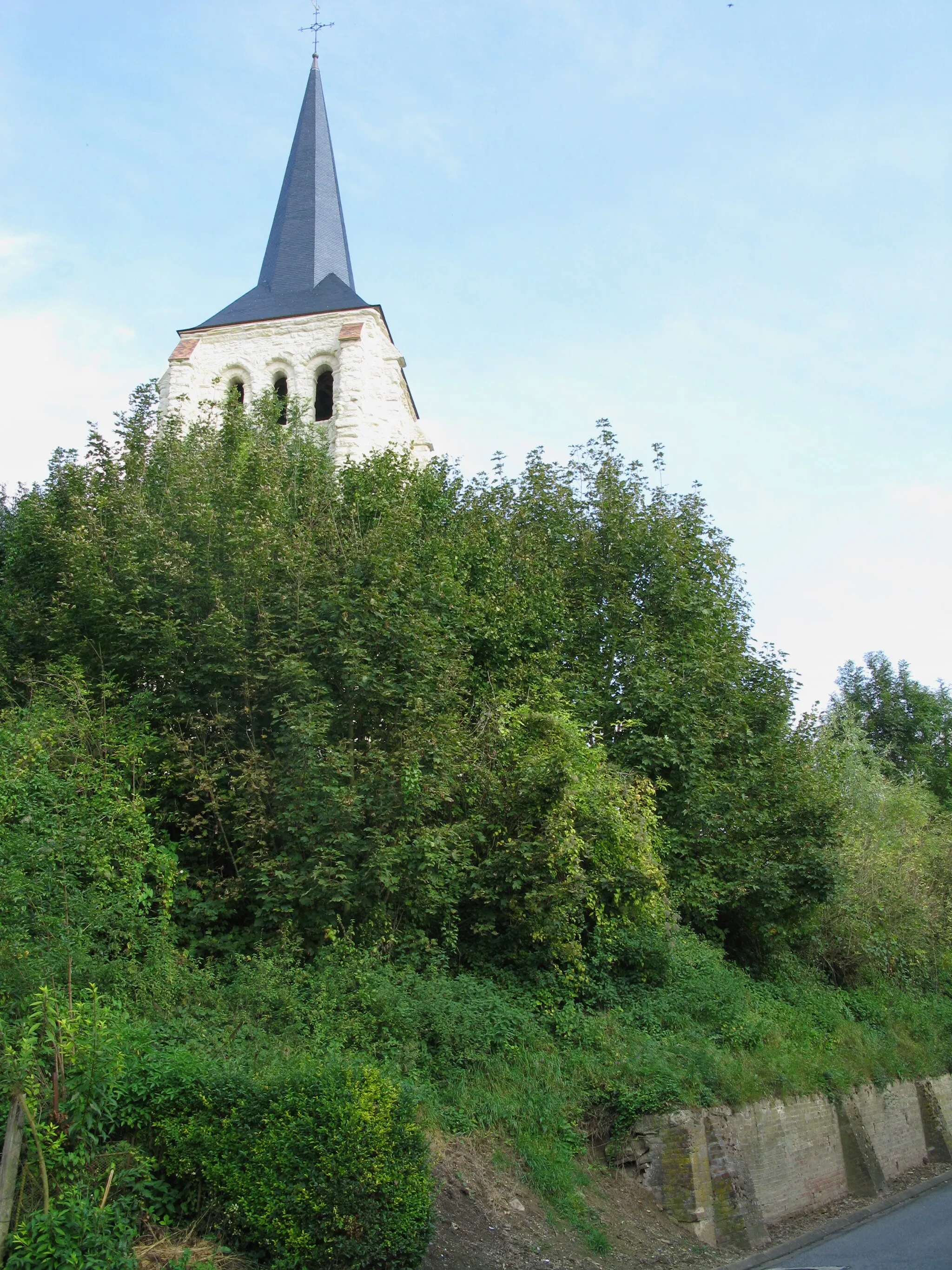 Photo showing: Tavaux-et-Pontséricourt (Aisne, France) -
Le clocher de l'église fortifiée.

Le clocher de pierre, d'un blanc éclatant dû à une restauration récente, surgit de la butte boisée surplombant une partie du village.