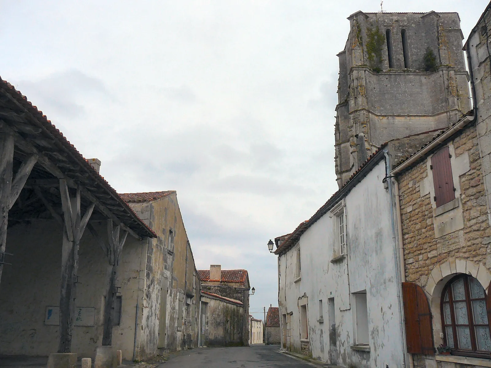 Photo showing: Street in the village center, with the ancient covered market and the gothique church. Saint-Jean-d'Angle, Charente-Maritime, Poitou-Charentes, France, Europe.