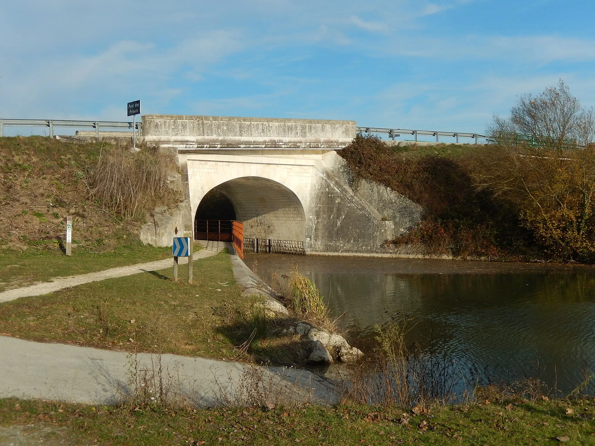 Photo showing: Saint-Ouen-d'Aunis, Charente-Maritime, France. Le pont des Prieurs, vu du sud. Ce pont permet à la route départementale 20 d'enjamber la Vélodyssée (EuroVelo 1, à gauche sur l'image), le canal de Marans (à droite sur l'image), et la voie ferrée reliant Nantes à Saintes (hors du cadre de la photo).