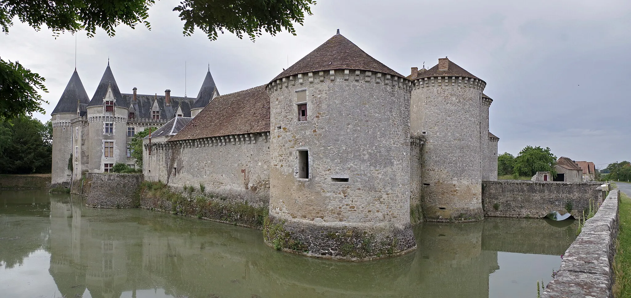 Photo showing: Bourg-Archambault (Vienne)
Château de Bourg-Archambault.
L'ensemble se compose se compose d'un enceinte flanquée de tours, d'un châtelet d'entrée et d'un logis très restauré au XIXe siècle.
Le château est constitué de deux parties, l'une médiévale et l'autre plus récente, entourées de douves.
Les tours à mâchicoulis, les larges douves et le châtelet d'entrée, sont un exemple de l'architecture militaire du XVe siècle. Le châtelet d'entrée était alors protégé par un double pont-levis et une ligne de mâchicoulis.
Le château actuel a été construit par Poncet de Rivière, chambellan du roi de France, Louis XI, sur un édifice plus ancien qui a été rasé. L'édifice est érigé en 1478.
Le logis actuel est constitué de deux logis (un résidentiel et l'autre militaire) qui seront réunis par Pierre de Sacierges, évêque de Luçon, seigneur du domaine à partir de 1494. Le nouveau logis constitue alors un bâtiment rectangulaire flanqué des deux tours déjà existantes. Une chapelle occupe le premier étage d'une des tours. L'architecte Charles Roques ajoutera trois tours circulaires supplémentaires en 1865.
Au XIIIe siècle et au premier tiers du XIVe siècle, la seigneurie appartient à la famille Chenac.
Vers 1338, gendre d’Hélie de Chenac, Odet de Rivière, hérite du château après la mort de son beau-père.
Poncet de Rivière, chevalier et seigneur de Château-Larcher, neveu et héritier d’Odet, devient propriétaire du domaine à la mort de ce dernier.
On trouve mention d'un ouvrage fortifié au début du XVe siècle. Par une lettre royale de 1412, on apprend que cet ensemble castral est vétuste et sert de refuge aux habitants en cas de nécessité. Les vestiges d'une tour, aujourd'hui rasée totalement, dans la cour, pourrait appartenir à l'ancien donjon. Ce premier édifice fut détruit, par ordre de Louis XI, vers 1468 alors que son propriétaire est Poncet de Rivière.
Le chevalier Poncet de Rivière, qui fut un des chefs de l'armée de Louis XI, aurait adhéré à un parti opposé au roi . Privé, à cause de ces intrigues, du commandement de sa compagnie de cent lances, mais avec une indemnité de 2.500 livres, ) et la charge de bailli de Montferrand (novembre 1465), il partit peu de temps après en pèlerinage à Jérusalem et à Sainte-Catherine du Mont-Sinaï (Journal de Jean de Roye, connu sous le nom de Chronique scandaleuse, édit. B. de Mandrot, t. I, p. 143-144).
En avril 1468, Poncet de Rivière abandonne le service de Louis XI pour se retirer à la cour de Bourgogne. Il prendra part à la campagne de Charles le Téméraire contre Louis XI. Lors des pourparlers qui aboutiront au traité de Péronne (14 octobre 1468), le duc de Bourgogne tenta de persuader le roi de France  d'y introduire un article en faveur Poncet de Rivière (et de Du Lau et d’Urfé), « et qu’il fust dit que leurs terres et estatz leur seroient renduz, comme ilz avoient avant la guerre ». Ce à quoi le roi répondit qu’il était prêt à accepter cette clause, si de son côté Charles voulait lui accorder la grâce
du comte de Nevers et de M. de Croy. Ce qui était inacceptable pour le Téméraire.
Le 13 janvier 1474, Jean Hardy, clerc et serviteur d'Ythier Marchant (maître
de la chambre aux deniers du feu duc de Guyenne), avait été mis en état d’arrestation. Cet homme s’était introduit dans l’entourage du roi et avait tenté de séduire des officiers de cuisine de la cour, pour glisser
du poison dans les mets destinés à la table royale. Dénoncé par ceux qu’il avait tenté de gagner à son criminel dessein, arrêté, jeté en prison, renvoyé devant une commission extraordinaire, mis à la torture à plusieurs reprises, il avait tout avoué. Il avait déclaré, en outre, que c’était Ythier Marchant qui l’avait envoyé dans ce but d’empoisonner le roi, et que Poncet de Rivière, au
courant de ce projet, l’avait encouragé.
Le 30 mars 1474, le Parlement  condamna Jean Hardy a être écartelé et décapité, sa tête plantée sur une lance devant l’hôtel de ville de Paris, ses quatre membres portés en quatre des bonnes villes des extrémités du royaume, le corps brûlé et réduit en cendres sur la place de Grève. Il fut exécuté le même jour.
Poncet de Rivière et Ythier Marchant, le 4 mai 1474, furent décrétés à prise de corps, mais hors d'atteinte, ils ne se laissèrent pas prendre, et la cour les condamna par contumace. Le procureur général requit contre eux deux la peine capitale ; néanmoins l’arrêt ne condamna Poncet qu’au bannissement à perpétuité et à la confiscation de corps et de biens envers le roi.
Poncet de Rivière fit jouer ses relations, et François II, duc de Bretagne, envoya à Louis XI des ambassadeurs spéciaux pour plaider la cause du condamné.  Finalement, le roi se contenta d’un serment solennel sur un fragment de la vraie croix, prêté par Poncet de Rivière, en présence du comte de Comminges, en l’église Saint-Lô près d’Angers. En mars 1478, Poncet de Rivière reçu l'autorisation de relever les fortifications que Louis XI avait fait raser. Poncet commença l’édification d’un nouveau château, peut-être achevé avant sa mort en 1487.
Ses héritiers, ruinés, vendirent le château en 1494 à Pierre de Sacierges, abbé de la Châtille, de Notre-Dame-la-Grande de Poitiers, et évêque de Luçon. Pierre de Sacierges commença aussitôt une série de travaux pour améliorer l’aspect résidentiel de la forteresse. Homme politique qui accompagna le roi en Italie, l'évêque résida peu à Bourg-Archambault, mais y mouru en 1514.
En 1591, lors de la huitième guerre de religion, la forteresse est prise, pillée et partiellement incendiée.
Au XVIIe siècle, le château subira le siège du seigneur de Cheronac, accompagné dede soldats, d'archers, et de cavaliers; celui-ci vient libérer sa nièce enlevée par Louis de Blanchart (ou Blanchard), écuyer et sieur de Bourg-Archambault. Ce dernier capitulera. Louis de Blanchart finira exécuté, pour meurtre et faux monnayage*, en 1656. Le château sera partiellement démantelé.
Ensuite, le château changera de mains à plusieurs reprises, et en 1835, l'édifice est acheté par Pierre (Jean?) Augier de Crémiers, ancien sous-préfet de Montmorillon, qui procédera une vaste rénovation. Ses descendants sont les actuels propriétaires.

Vers le milieu du XVIIe siècle, le Haut-Poitou fut inondé de fausse monnaies. Le seigneur de Bourg-Achambault, Louis de Blanchard, ayant assassiné son voisin, le seigneur de Chanteloube, le prévôt fit des perquisitions au château et y découvrit le matériel nécessaire pour fabriquer de la fausse monnaie. Le 13 novembre 1656, Blanchard fut décapité sur la place de Notre-Dame-la-Grande à Poitiers. Voir :
Matteo Ferrari, Bourg-Archambault, château (châtelet d’entrée), base-armma.edel.univpoitiers.fr/monument/chateau-bourg-ar..., consulté le 21/06/2021
mariepierre86.centerblog.net/540-patrimoine-et-personalit...
corpus.enc.sorbonne.fr/actesroyauxdupoitou/tome8/1130
www.francebleu.fr/emissions/histoires-du-poitou-avec-patr...
www.lanouvellerepublique.fr/vienne/commune/bourg-archamba...

Essai sur les Monnaies Frappées en Poitou par Lecointre-Dupont. Poitiers 1840.