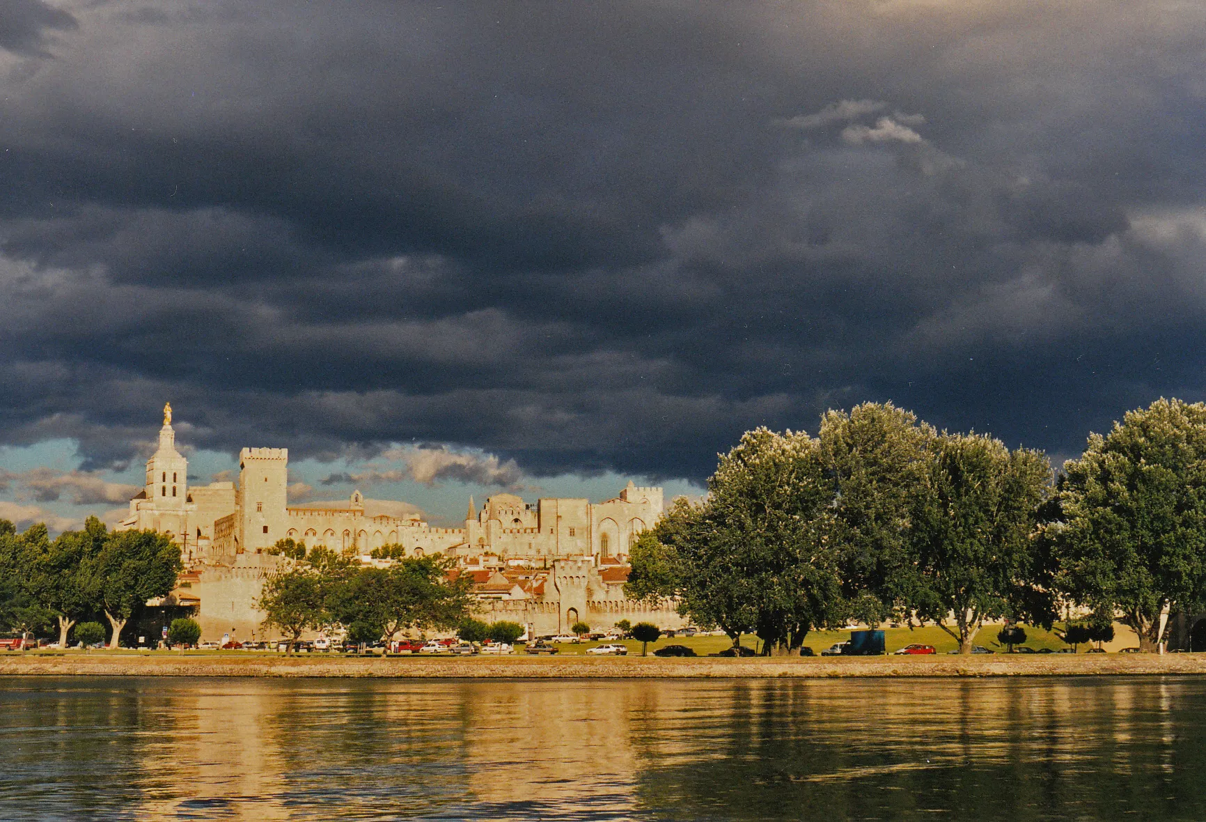 Photo showing: Photo: Summer thunderstorm at the Festival d'Avignon in July 2000
Location: Île de la Barthelasse south (Camping du Pont) near the Pont Benezet (Pont d'Avignon)

Objects: Eastern arm of the Rhone, city wall, Pope's Palace, upper city center, traffic jam at the end of the day on the 'Boulevard du Rhone', left beginning of the 'Jardin des Doms'