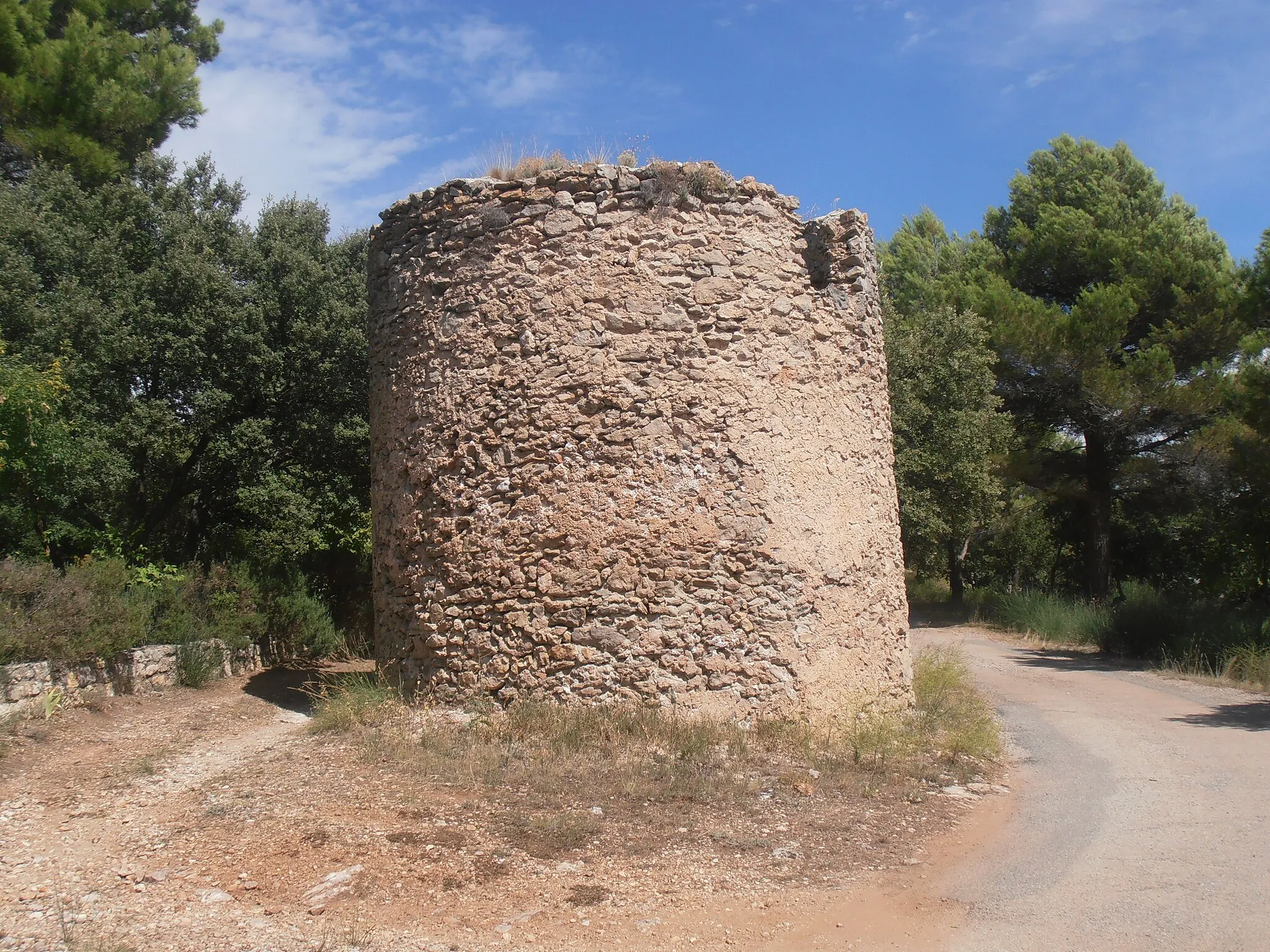 Photo showing: Var, Moissac-Bellevue, Ruines d’un moulin à blé.
Situation et histoire : Situé sur le chemin qui mène à la chapelle Notre-dame-de-la-Roque (*), Le Plan Deffends. Ce bâtiment semble correspondre aux ruines d’un moulin à blé de type provençal. Pays du vent et pays du blé, la Provence compte de nombreux moulins à vent introduits par les Croisés de retour de Terre Sainte (source : livret 2019 de présentation du village). 
(*) Parcelle n° 247 - Feuille 000 B 02 - Commune : MOISSAC-BELLEVUE (83630)

Description sommaire : Plan rond ; Murs maçonnés en moellons calcaires hourdés au mortier et enduits ; Porte en pierres de taille clavées et surmontée plus haut par une petite baie ; Traces d’ancien escalier à l’intérieur ; Absence de toiture (sources : fiches patrimoine du PLU).