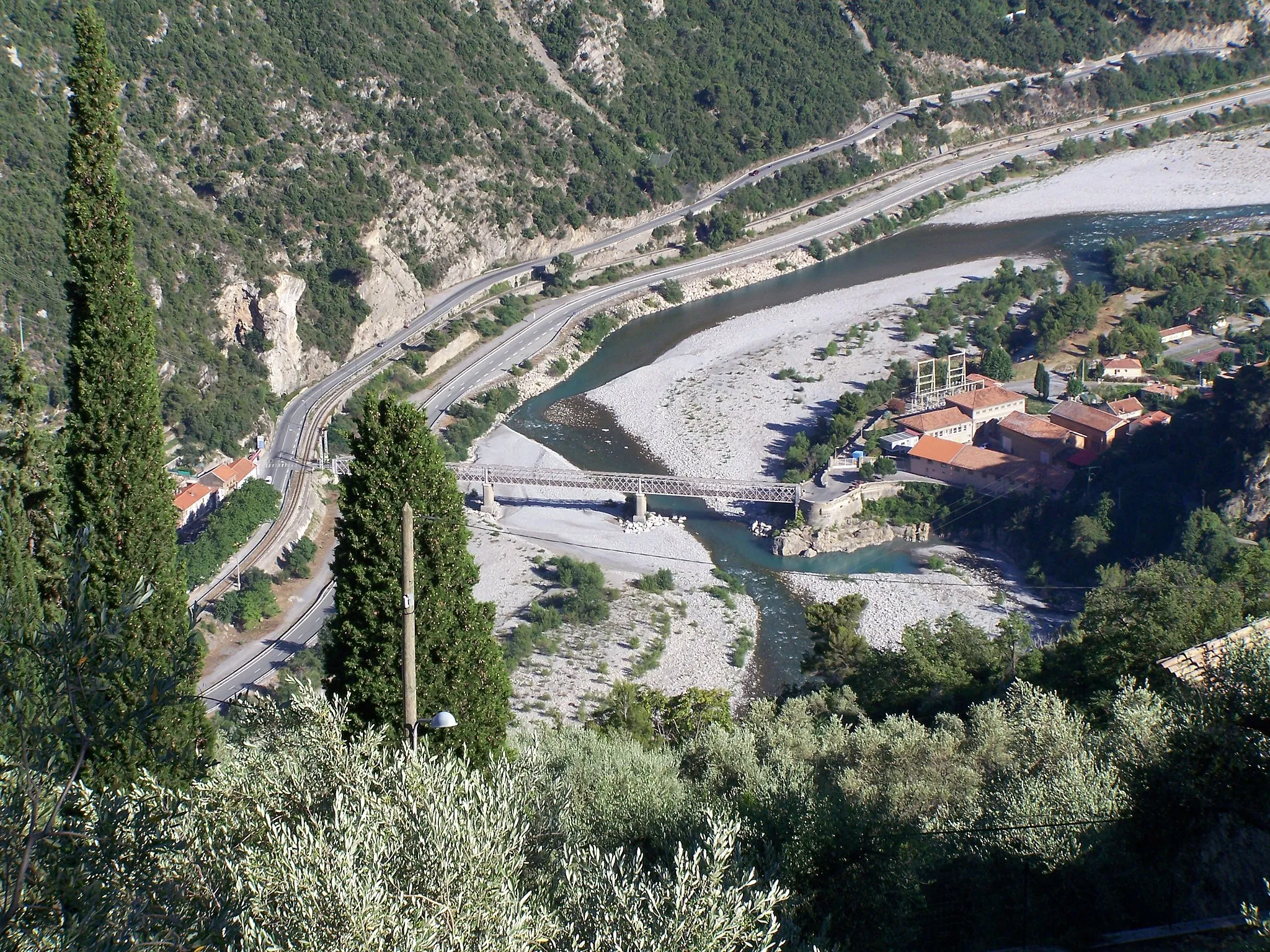 Photo showing: Quartier du Gabre sur la commune de Bonson (Alpes-Maritimes, France), en face de Plan du Var,  avec le pont du Gabre et l'usine électrique du Gabre construite en 1890 pour alimenter en électricité les tramways de Nice. Sur l'autre rive du Var, on peut voir la route de Digne (ex-nationale 202, actuellement départementale 6202) et la voie ferrée des Chemins de Fer de Provence ("Train des Pignes").