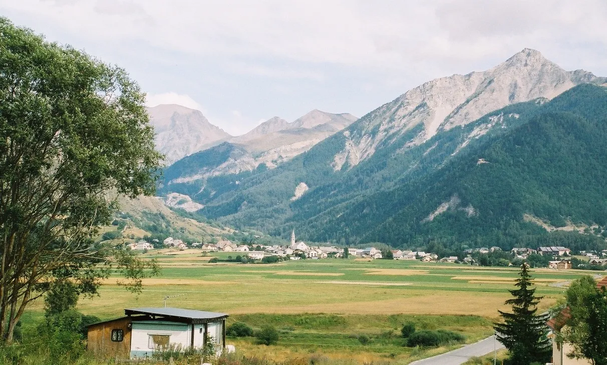 Photo showing: La plaine d'Ancelle et la vallée de la Rouanne vues du hameau de St Hillaire (commune d'Ancelle). Le village est surplombé par l'aiguille d'Ancelle. Au fond de la vallée pointe le sommet de la Coupa.