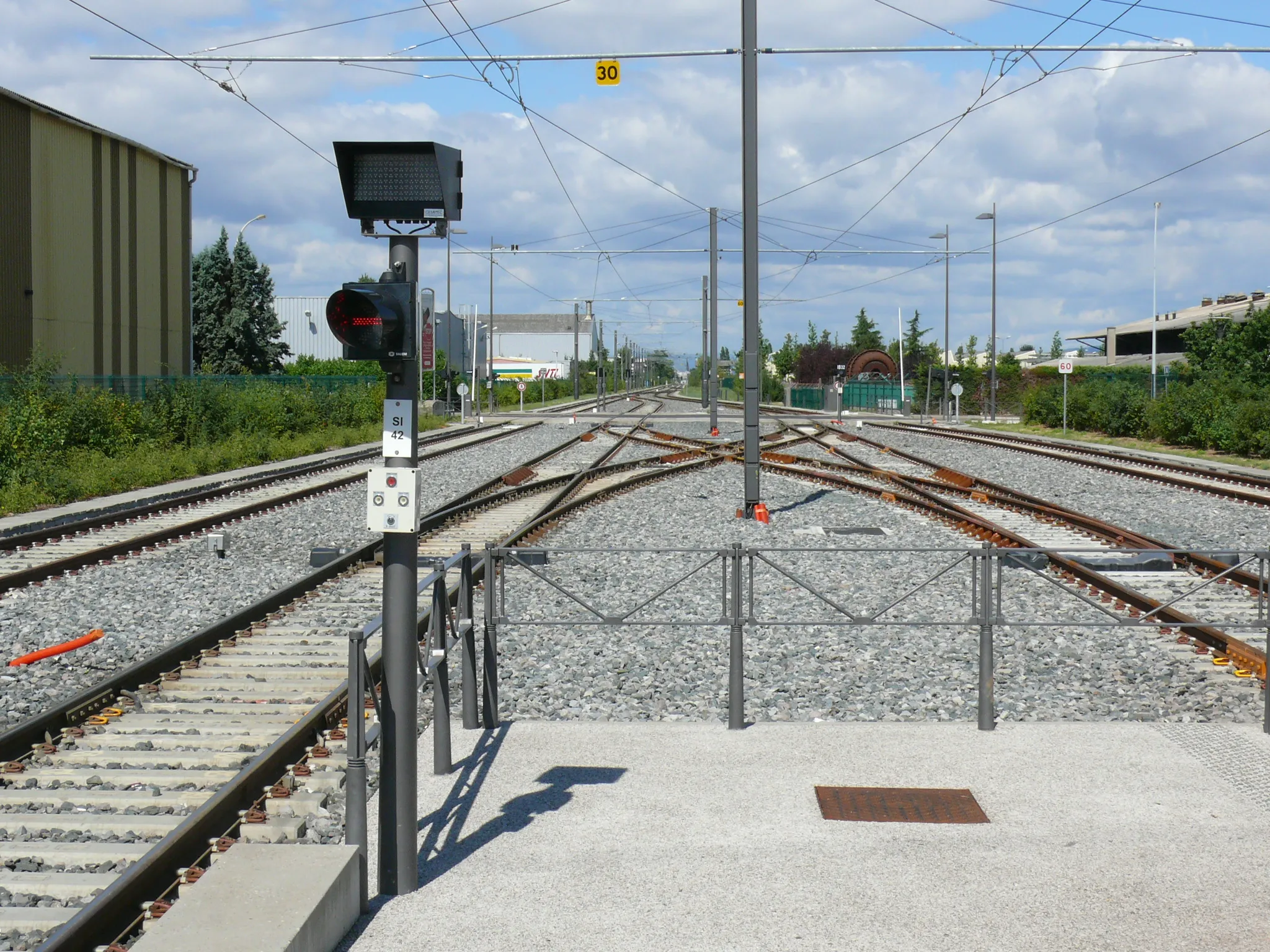 Photo showing: Tramway de Lyon — T3 et Rhônexpress : Appareils de voie de l'avant gare de Meyzieu. Les deux voies centrales constituent le terminus de la ligne T3, et les deux voies extérieures serviront au passage des rames de Rhônexpress, la liaison rail-aéroport desservant l'aéroport de Lyon Saint-Exupéry. La bretelle double visible au premier plan vient d'être installée, dans le cadre des travaux de mise en service de Rhônexpress. En effet, depuis la mise en service de T3, seule la voie à gauche du quai était utilisée par T3 en service commercial.