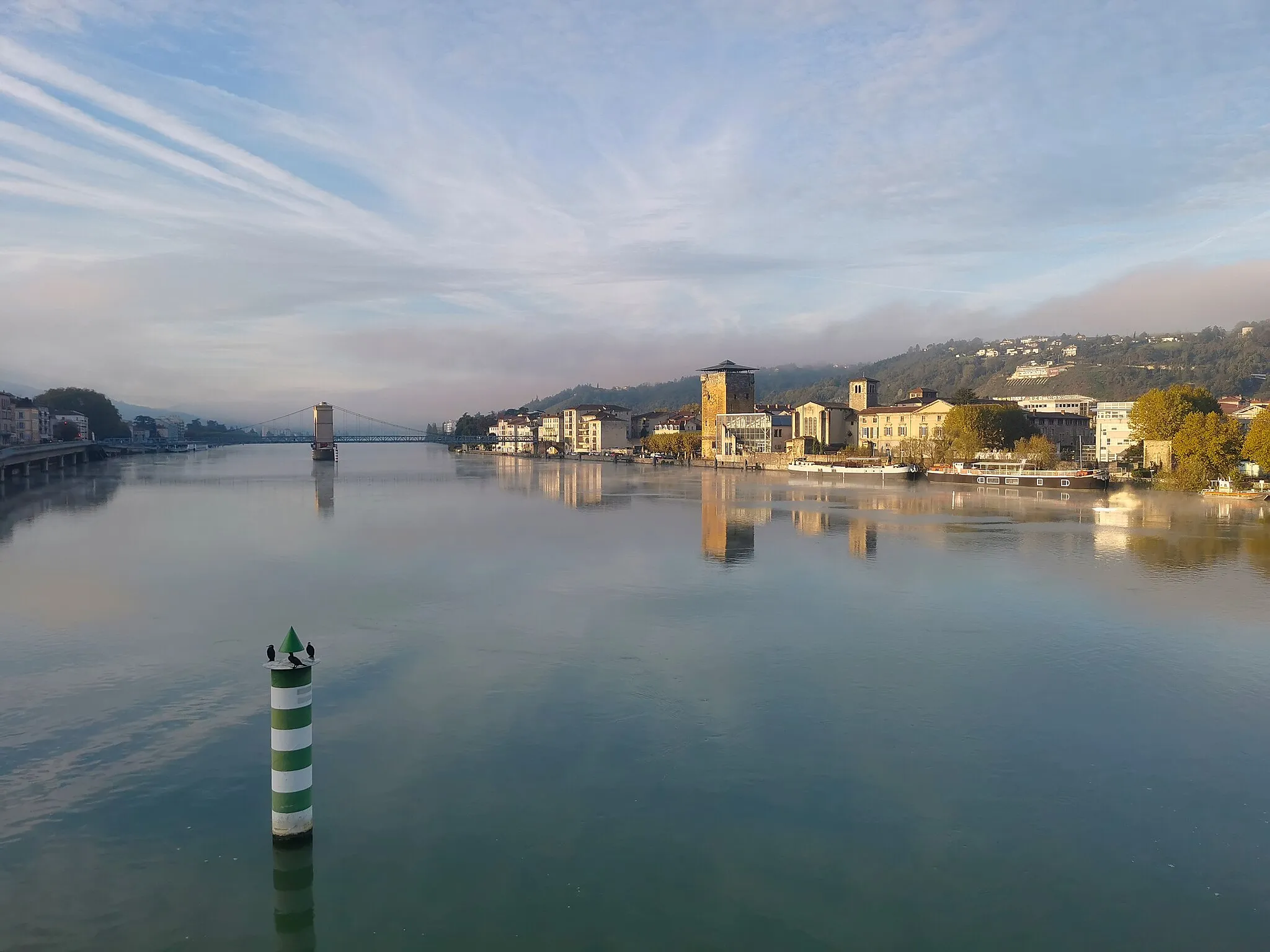 Photo showing: An early morning view of the Rhône from the Lattre-de-Tassigny bridge.  In the background the passerelle connecting Sainte-Colombe (Rhône) (on the right) with Vienne (Isère).  The Tour des Valois is the well lit tower on the right. In the foreground, three cormorants on a buoy.