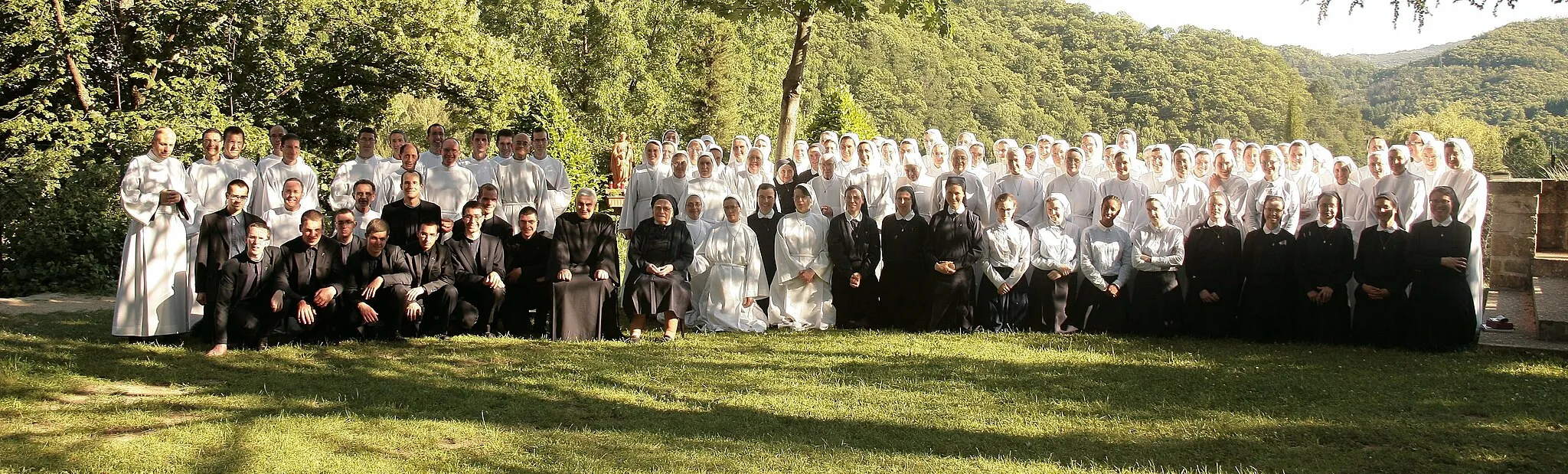 Photo showing: Sur cette photo, des frères et des sœurs entourent le Père et la Mère supérieurs de la Famille Missionnaire de Notre-Dame, connue aussi sous le nom de Famille Domini. Les religieux en tunique blanche sont les profès perpétuels, engagés à vie à la suite du Christ par les vœux religieux. En bleu marine, on distingue les profès temporaires, les novices et les postulants. La photo a été prise à Saint-Pierre-de-Colombier, maison-mère de la congrégation.