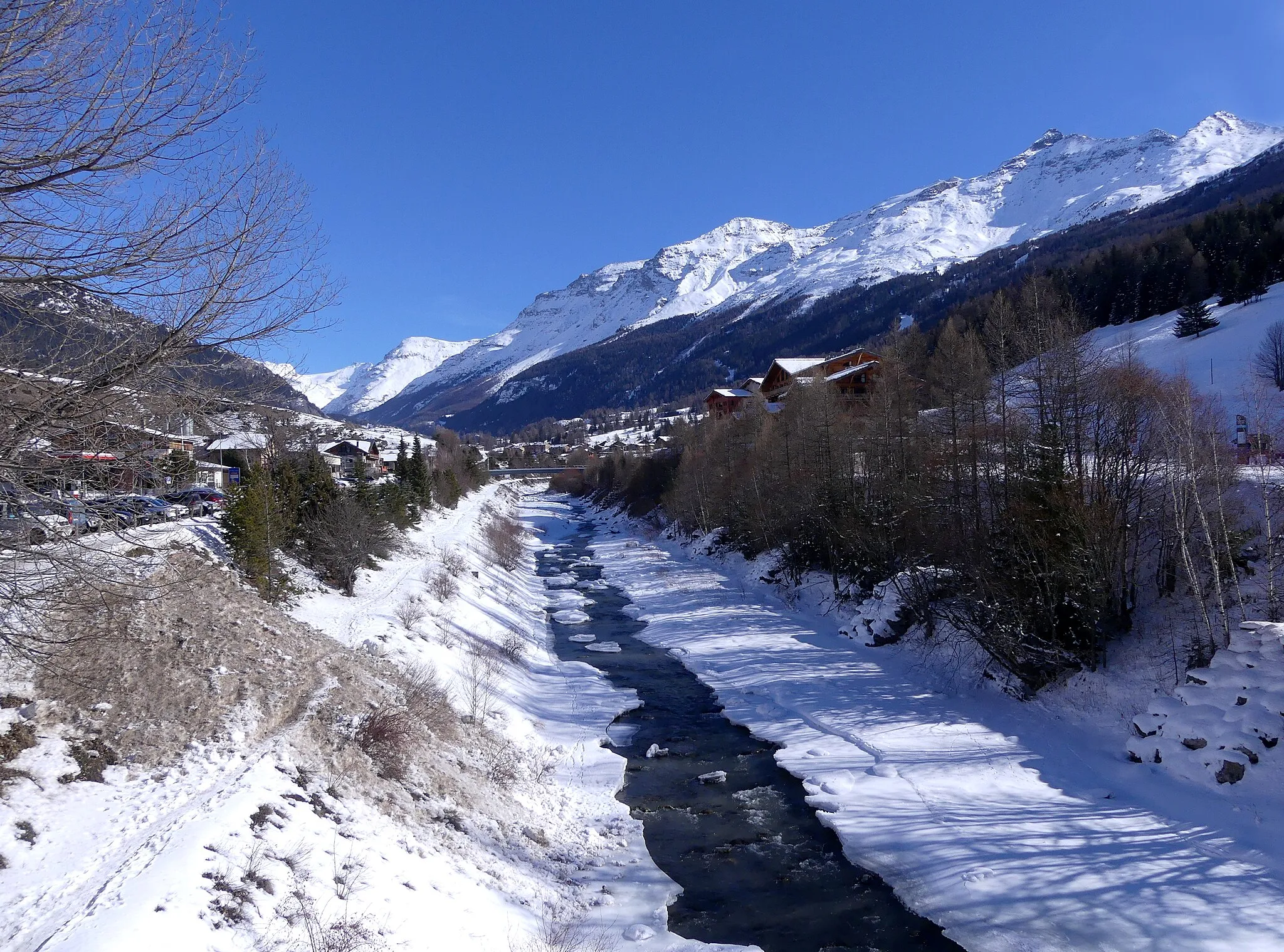 Photo showing: Sight, in winter, of partly frozen Arc river crossing Lanslebourg-Mont-Cenis village and ski resort, towards the east, in Maurienne valley, Savoie, France.