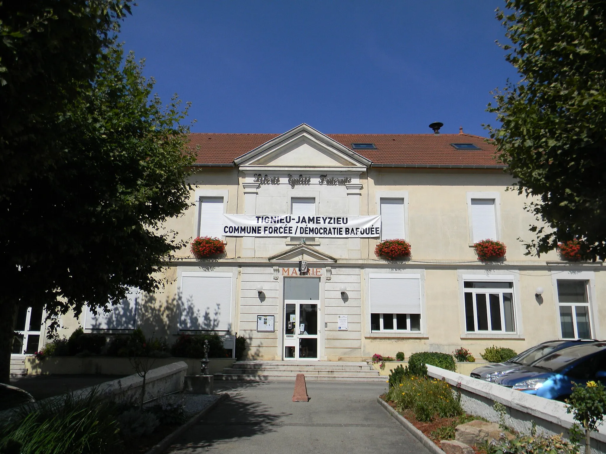 Photo showing: Mairie de Tignieu affichant une banderole "Tignieu-Jameyzieu - Commune forcée / Démocratie baffouée".