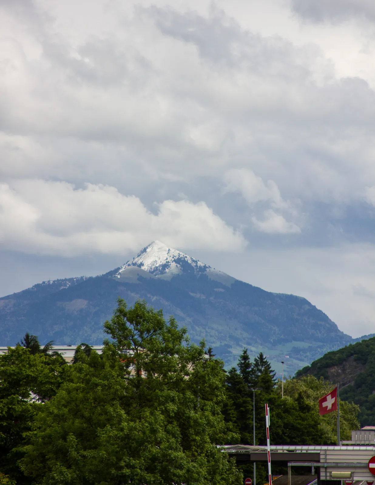 Photo showing: 500px provided description: Looking at the white capped Mt Blanc from the overpass above the france swiss border in Thonex. [#trees ,#sky ,#landscape ,#mountains ,#travel ,#blue ,#clouds ,#tree ,#building ,#snow ,#green ,#geneva ,#mountain ,#border ,#flag ,#France ,#Switzerland]