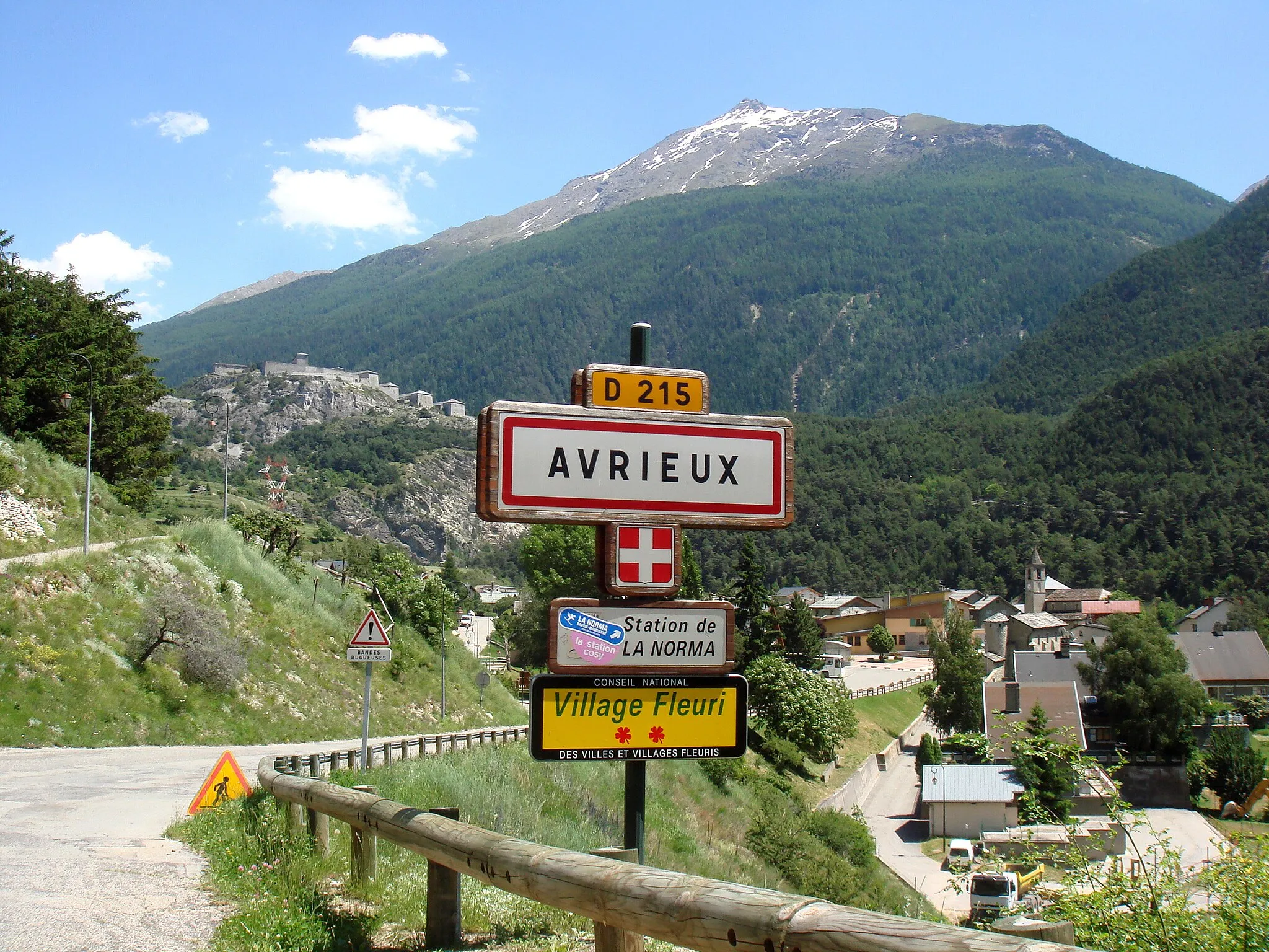 Photo showing: Name plate of Avrieux, a village in the Savoie department in the Rhône-Alpes region in southeastern France. In the background the Pointe de Longe Côte (3102 metres)