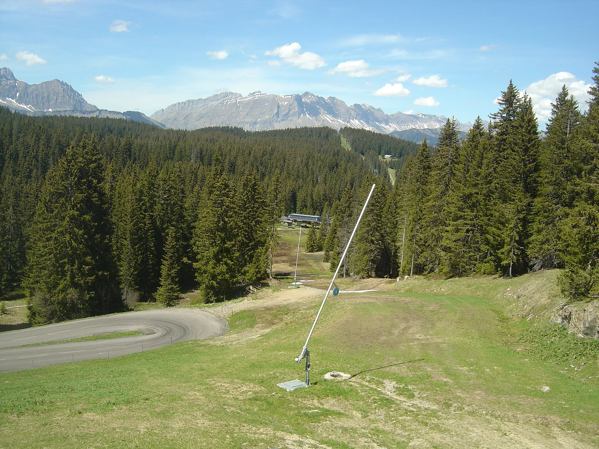 Photo showing: Route du versant nord-ouest du col des Saisies. Lacet à la fin de la route domaniale de Crest-Voland et vue plus bas sur le télésiège de Covetan. Au fond le massif des Aravis.