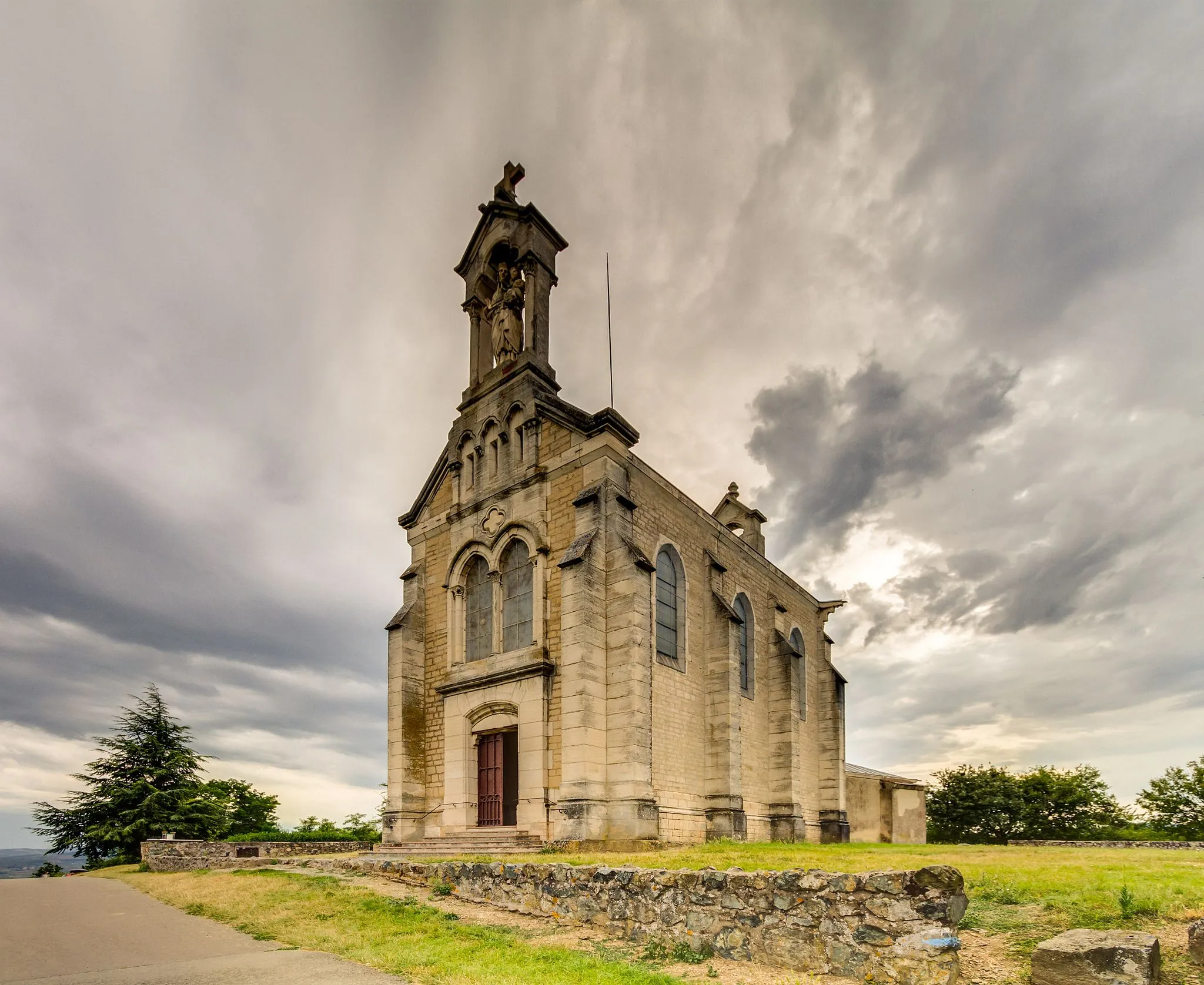 Photo showing: Notre-Dame aux Raisins chapel (Notre-Dame of grapes chapel), at the top of mount Brouilly, in Saint Lager, Rhône, east France. This picture is a blending of three exposures processed to enhance the dramatic mood given by the sky.