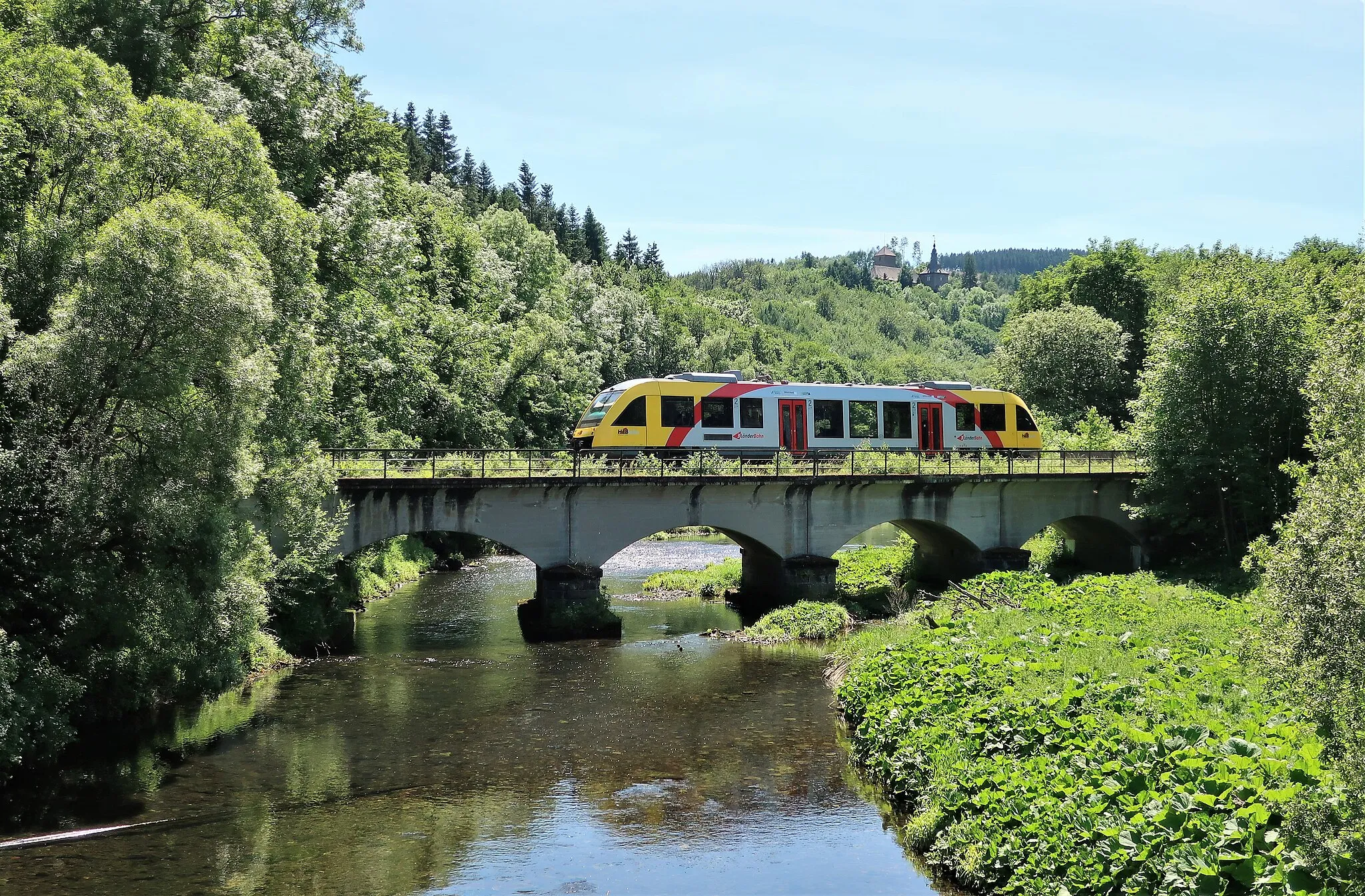 Photo showing: Eisenbahnbrücke der Bahnstrecke Finnentrop-Olpe über die Bigge im Attendorner Ortsteil Biggen. Im Hintergrund Burg Schnellenberg.