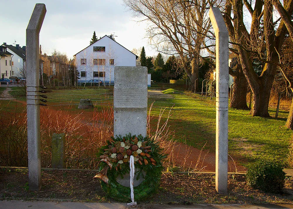 Photo showing: Monument by Anselm Treese to the victims of Annen labor camp, a subcamp of Buchenwald at the corner of Westfeldstraße and Immermannstraße in the Annen neighborhood of Witten, Germany. The obelisk lies on the perimeter where the fence of the labor camp once stood. Since the 1950s, houses were built on the land and, of the camp, there is only a small portion of open space left, seen behind the obelisk. This remaining space will not be developed, rather is to be kept as a reminder of the victims.
