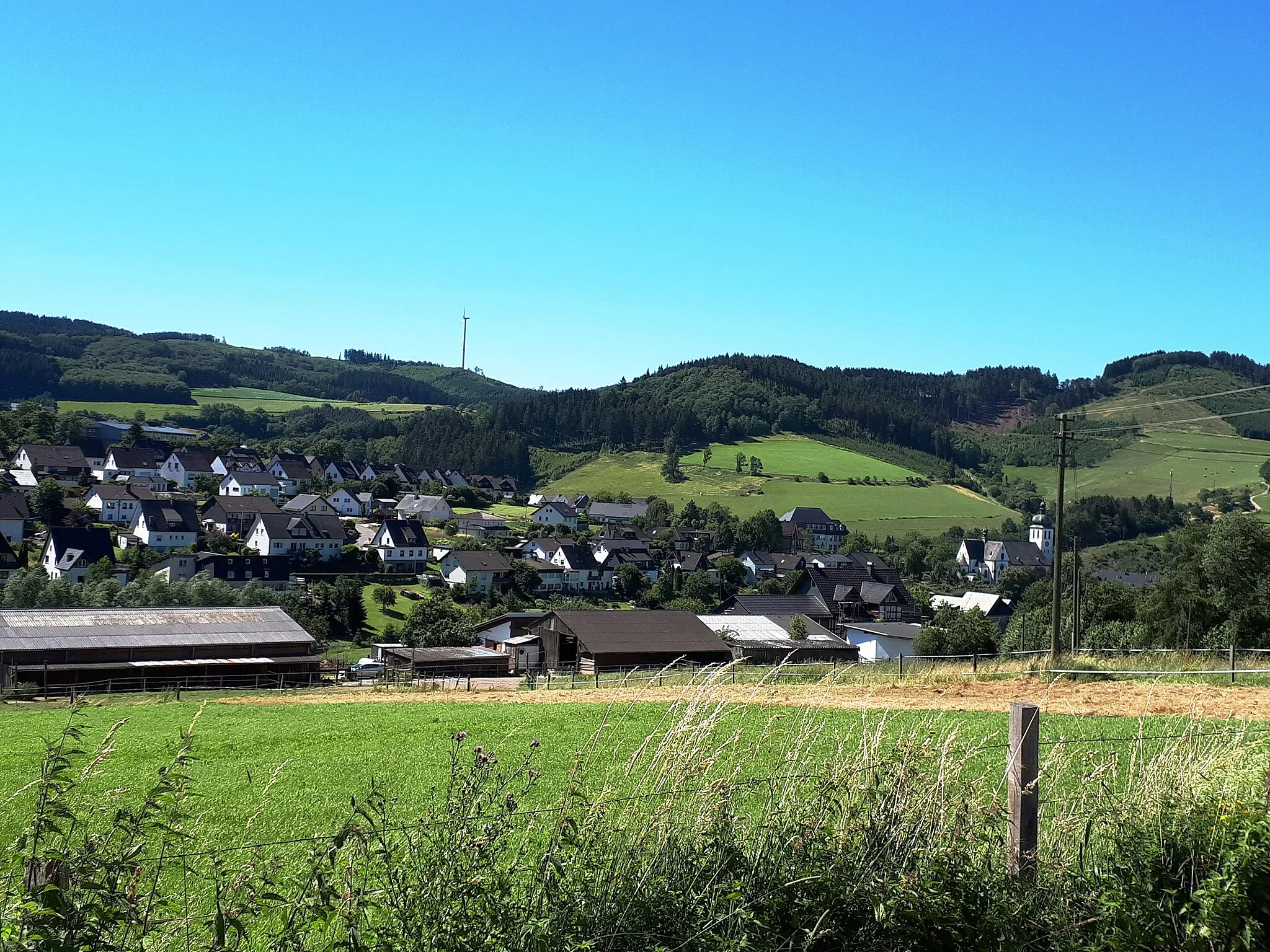 Photo showing: Elspe aus der Sicht vom 1904 errichteten Wasserhäuschen (am Feldweg Richtung SGV - Hütte Oberelspe). Rechts im Bild Pfarrkirche St. Jakobus d.Ä.