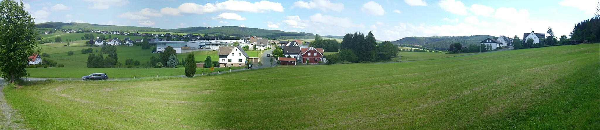 Photo showing: Blick auf Rückershausen und die Berge Birkenhecke (661,2 m, links), Ebschloh (686,5 m, links der Mitte), Rammelsberg (637,2 m, rechts der Mitte, etwas verdeckt) und Hohes Haupt (650,8 m, rechts) – siehe Udeuschle